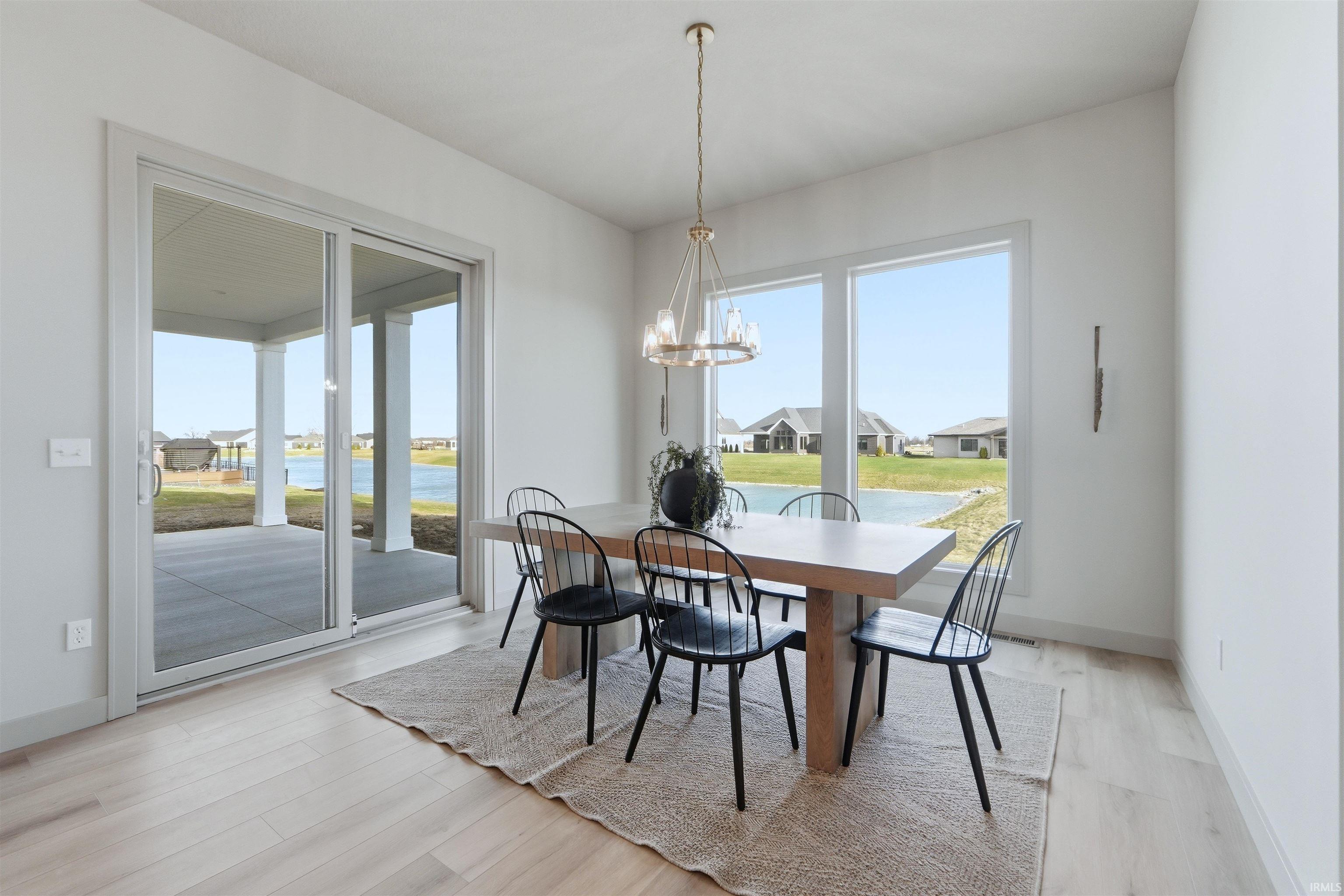 Dining area with light wood finished floors, hanging lights, a water view, and a residential view