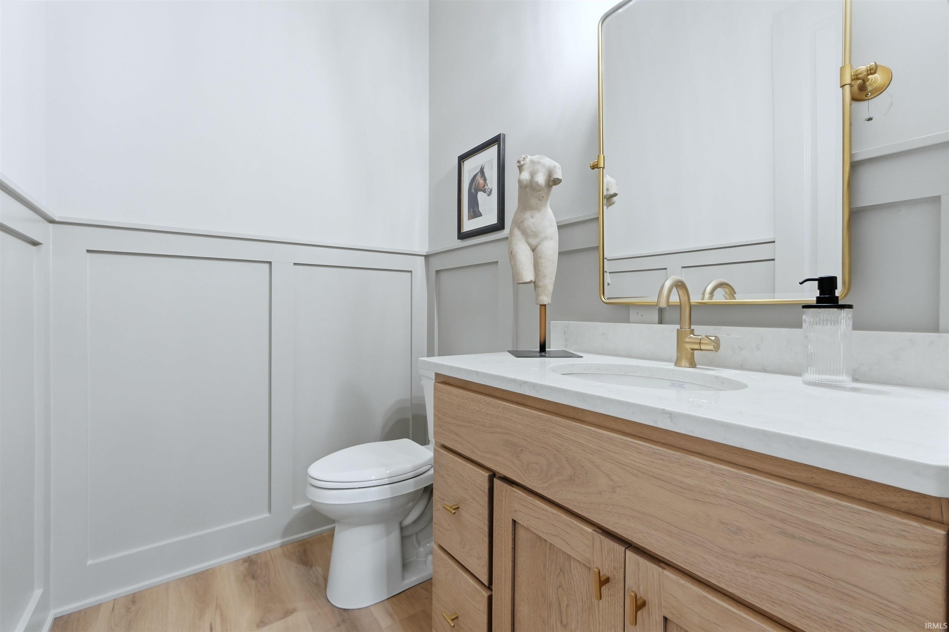 Bathroom featuring vanity, light wood-type flooring, a decorative wall, and a wainscoted wall
