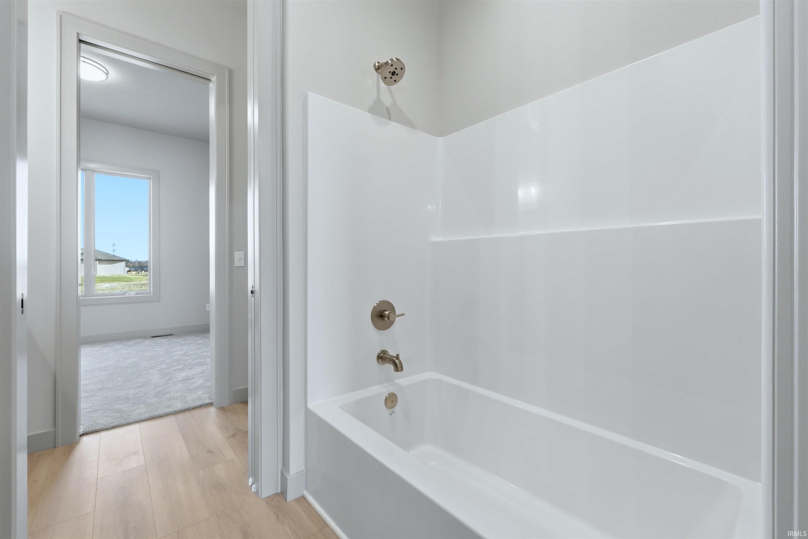 Bathroom with shower / bathtub combination and light wood-style flooring