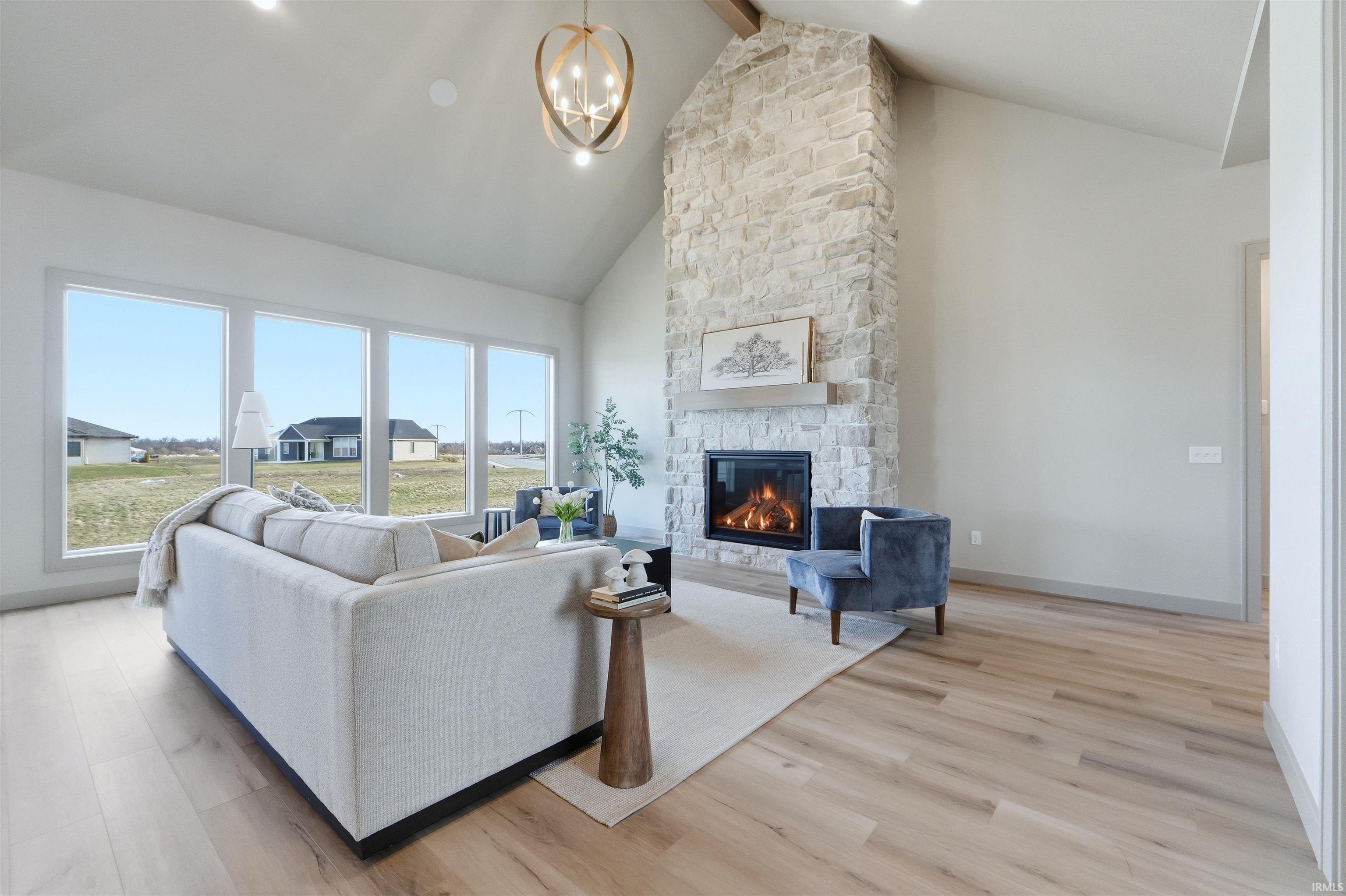 Living area with light wood-type flooring, suspended lighting, and a fireplace