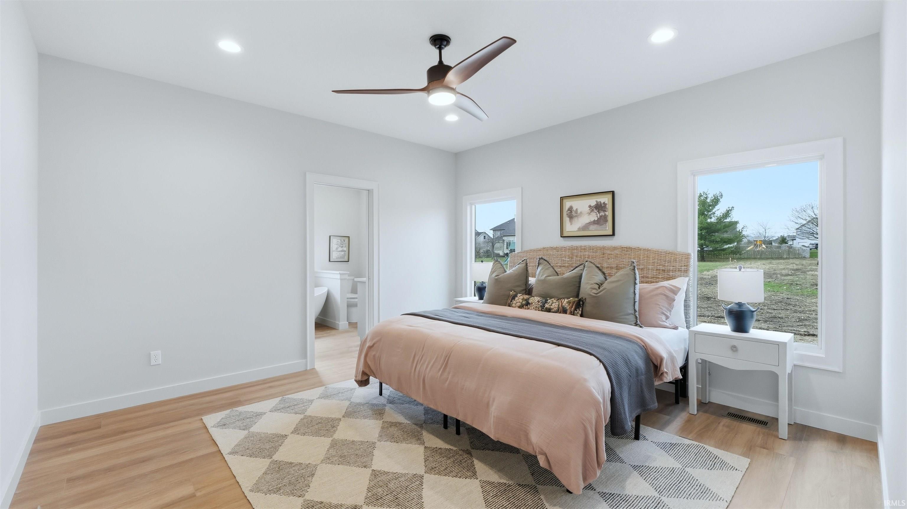 Bedroom featuring ensuite bathroom, light wood-style flooring, ceiling fan, multiple windows, and recessed lighting