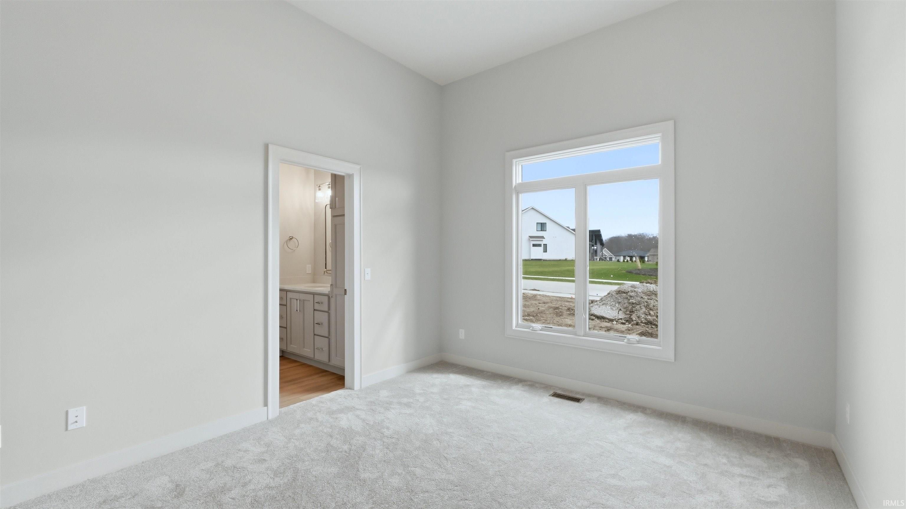 Unfurnished bedroom featuring light carpet and ensuite bath