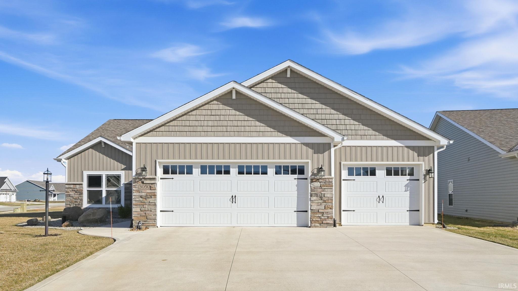 Craftsman-style home featuring stone siding, an attached garage, driveway, and board and batten siding