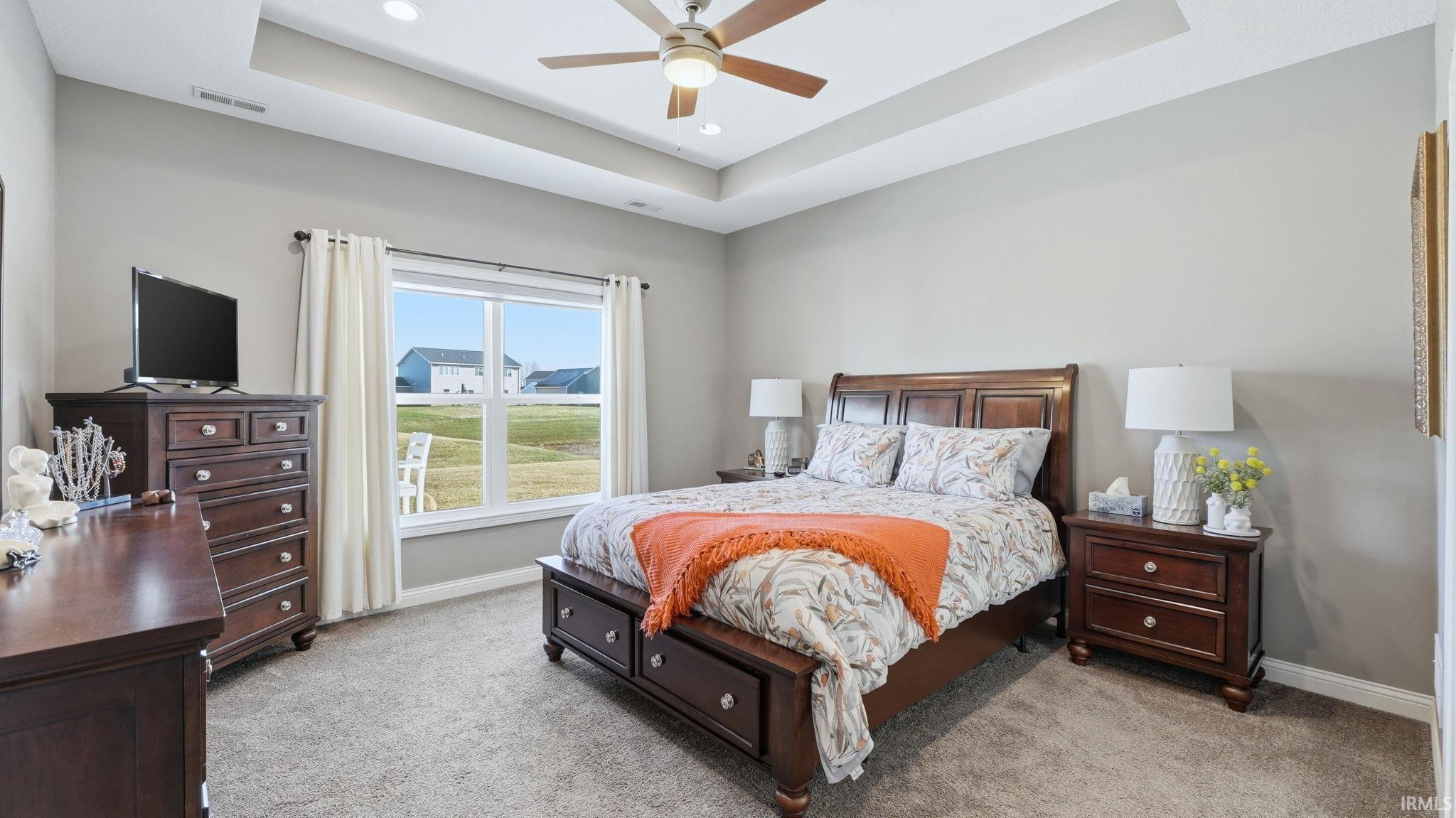 Bedroom featuring a raised ceiling, light colored carpet, ceiling fan, and recessed lighting
