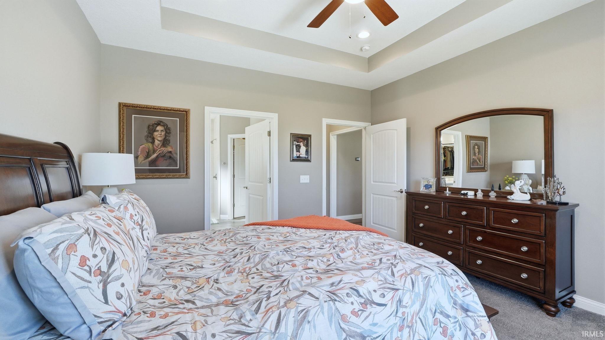 Carpeted bedroom with ceiling fan and a raised ceiling