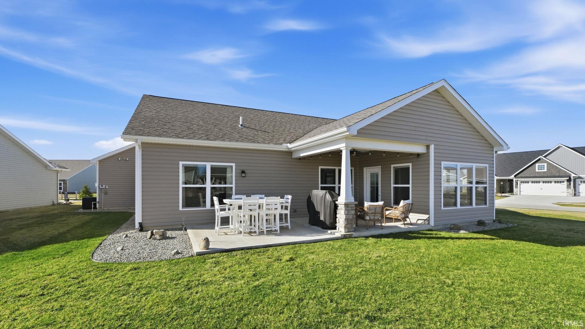 Back of property featuring a yard, a patio area, and a shingled roof