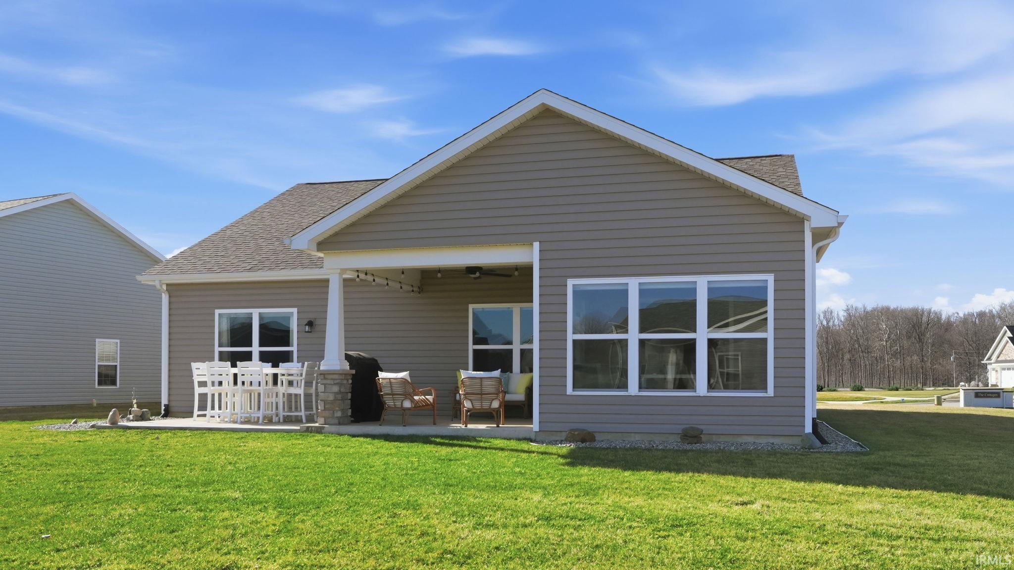 Rear view of house with a patio area, a yard, and roof with shingles