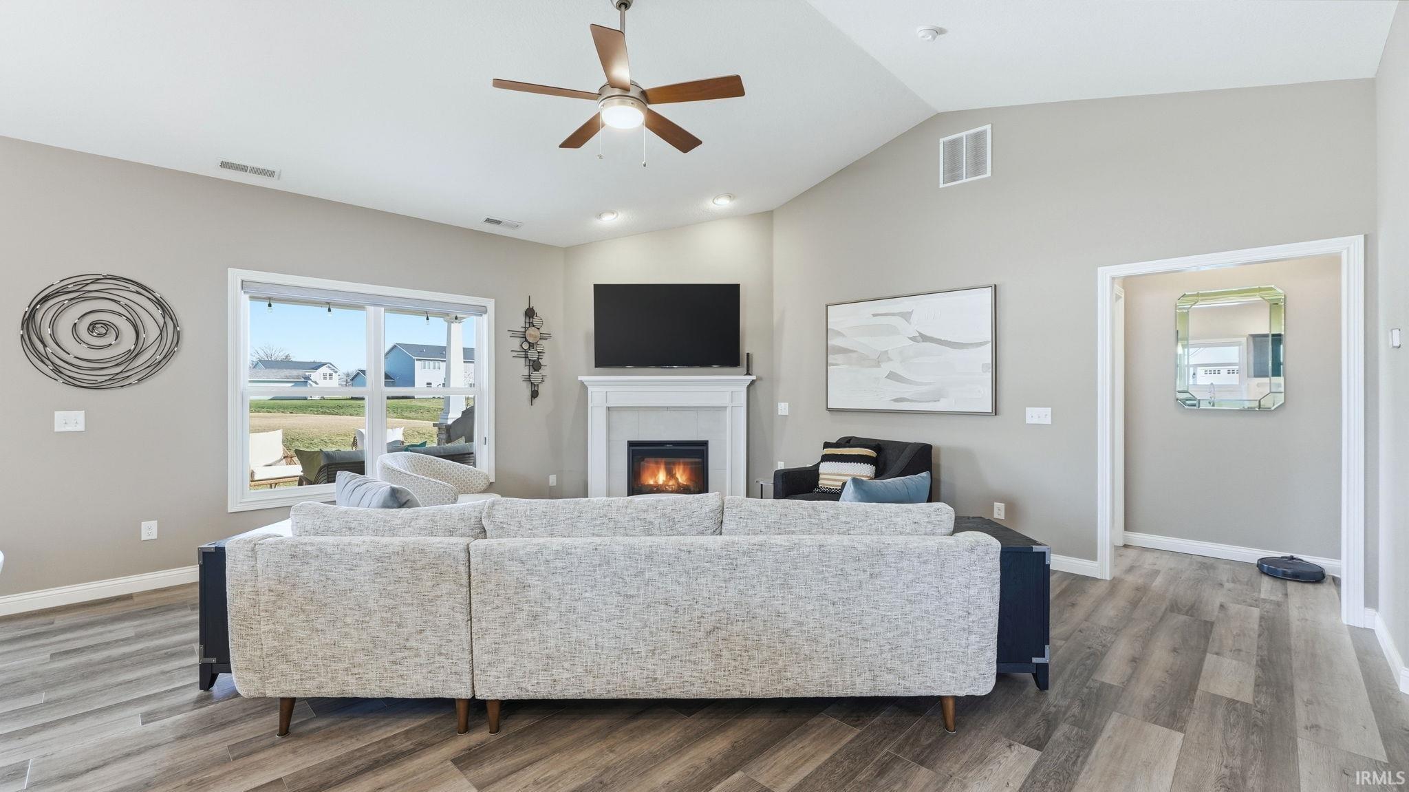 Living area with ceiling fan, light wood-style flooring, a fireplace, and lofted ceiling