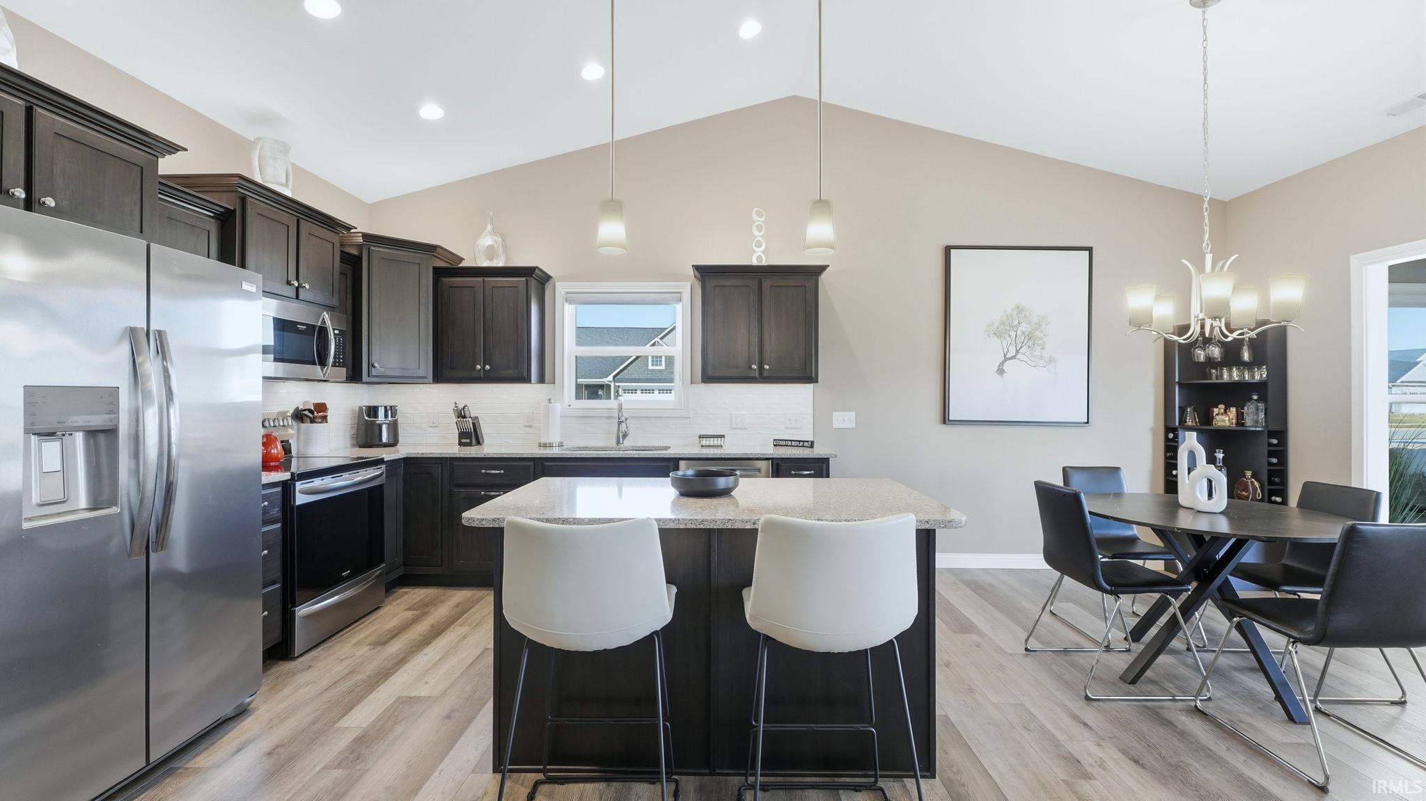 Kitchen featuring stainless steel appliances, a center island, light wood-style floors, and tasteful backsplash