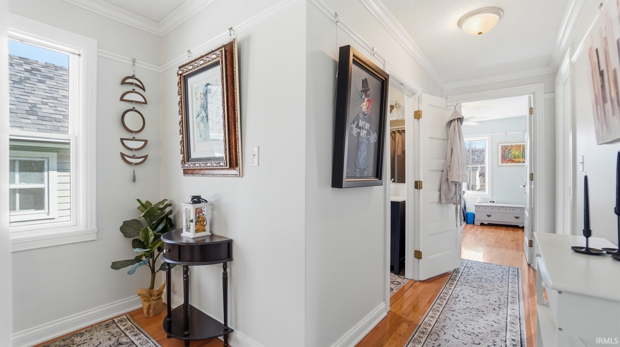Hallway with crown molding and light wood finished floors