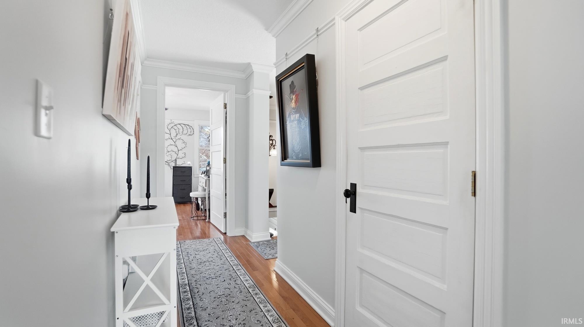 Hall with ornamental molding and light wood-style floors
