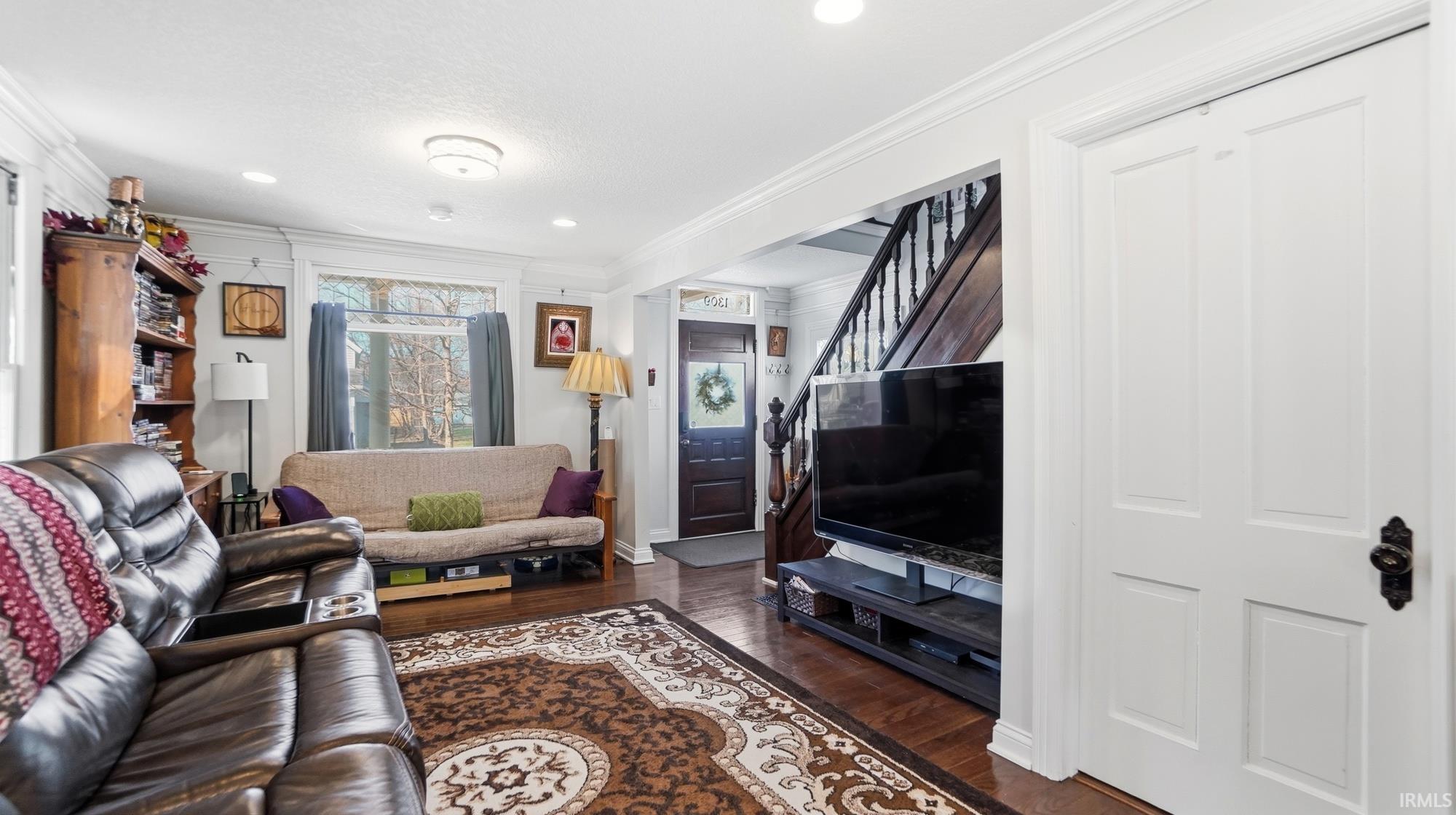 Living area with ornamental molding, dark wood finished floors, and recessed lighting