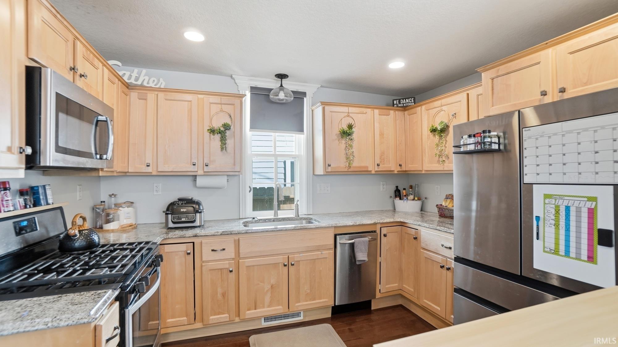 Kitchen with light wood finish cabinets, stainless steel appliances, light stone counters, and recessed lighting