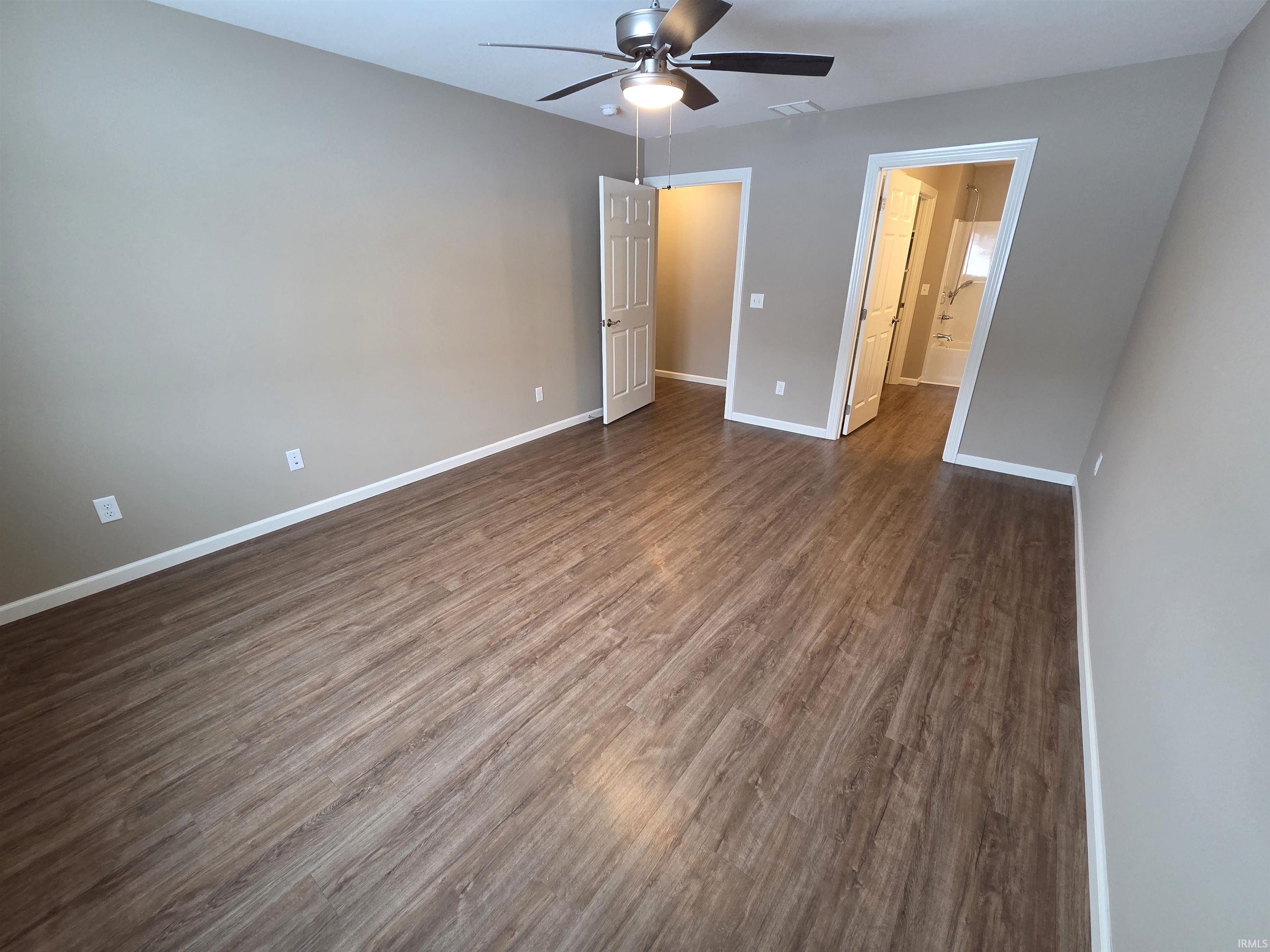 Unfurnished bedroom with dark wood-style flooring and a ceiling fan