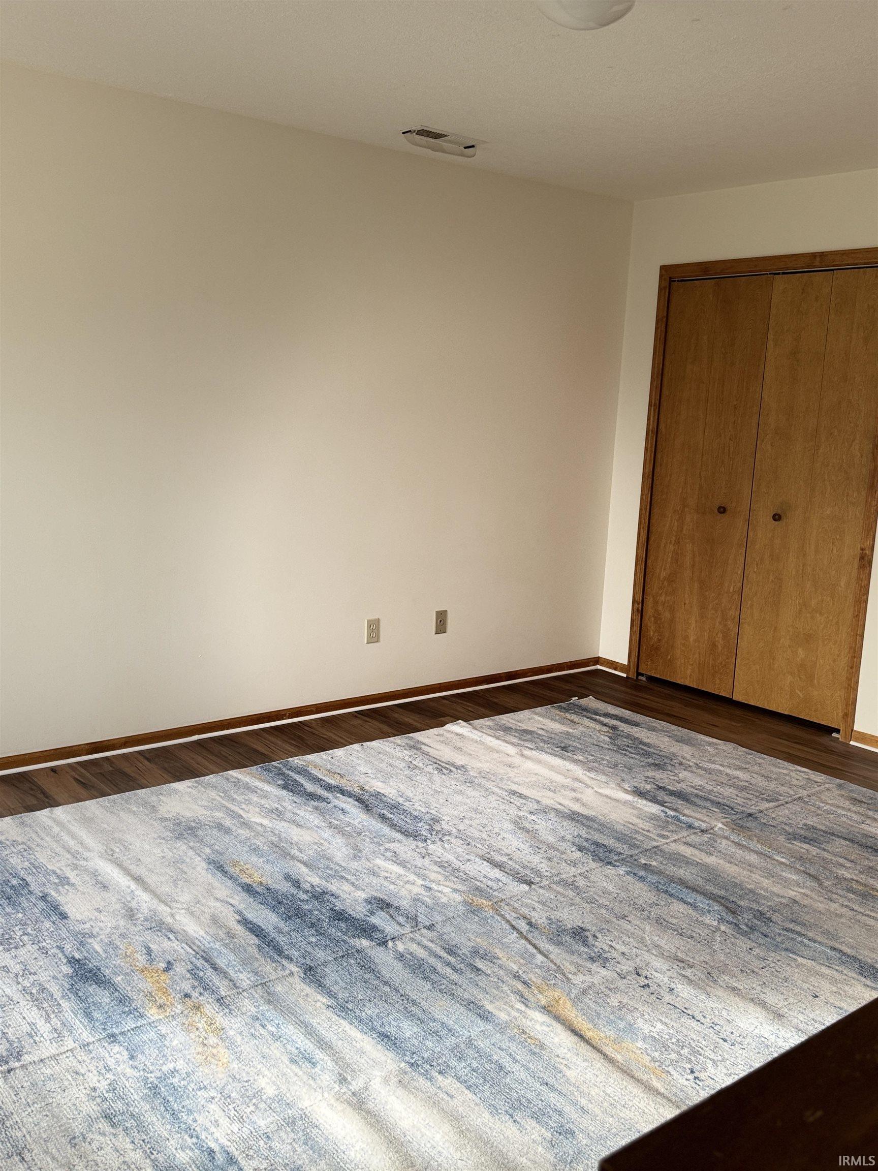 Unfurnished bedroom with a closet and dark wood-style flooring