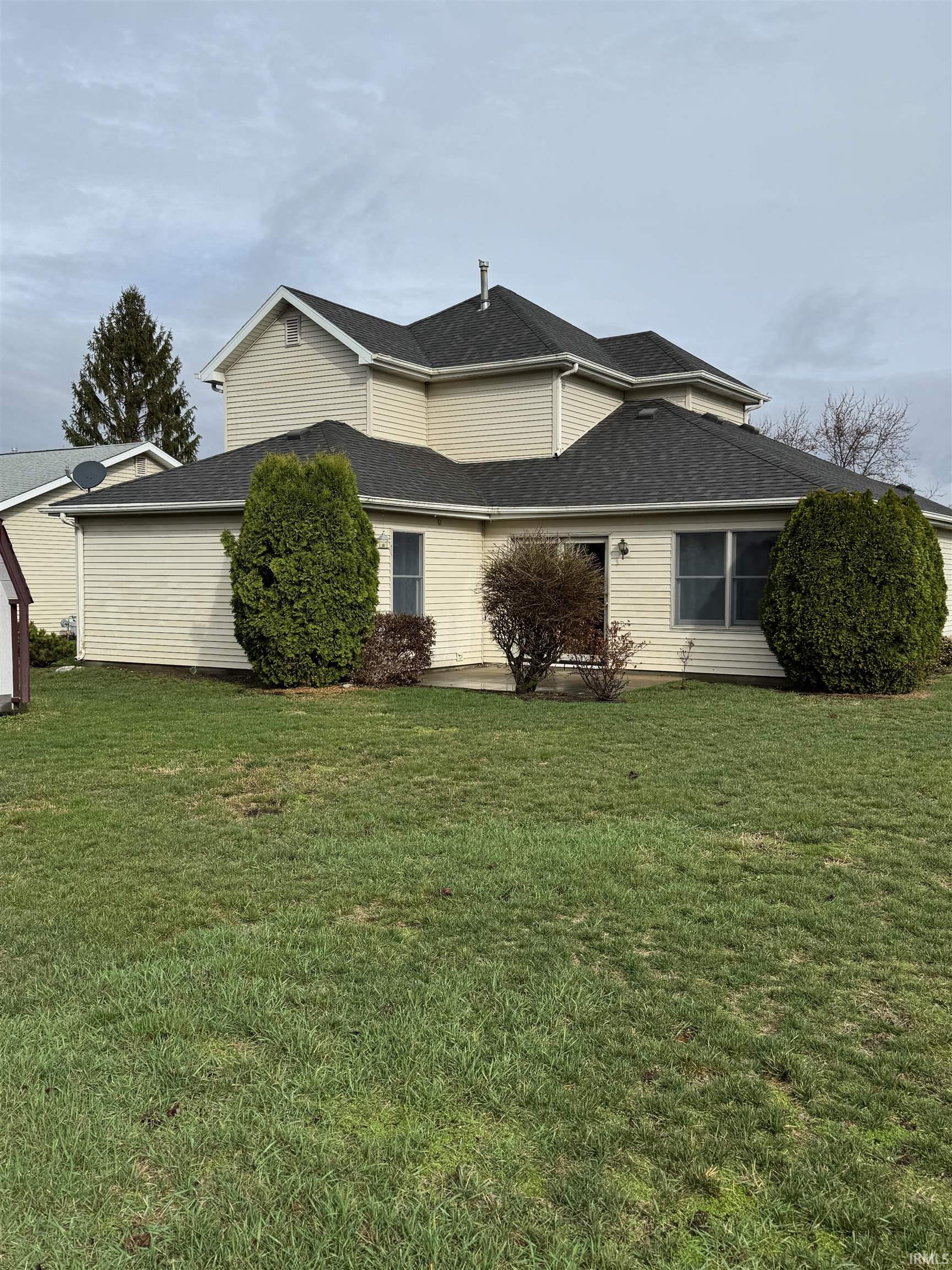 View of property exterior with a lawn and a shingled roof