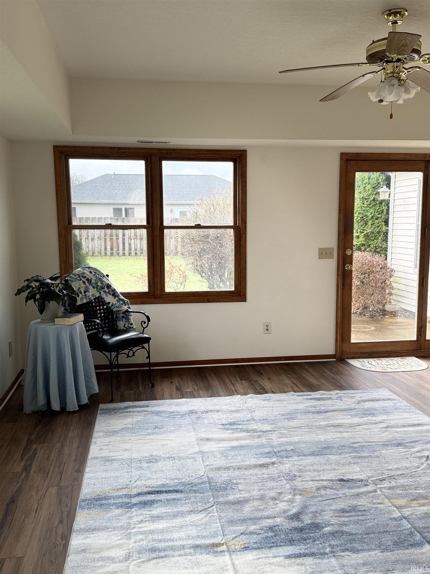 Living area featuring a ceiling fan, plenty of natural light, and dark wood finished floors