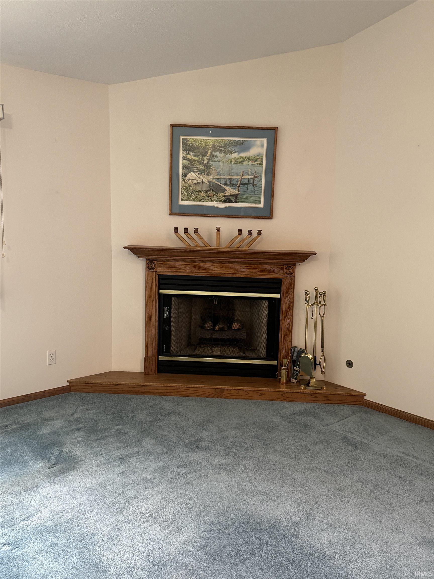 Unfurnished living room featuring a glass covered fireplace and carpet