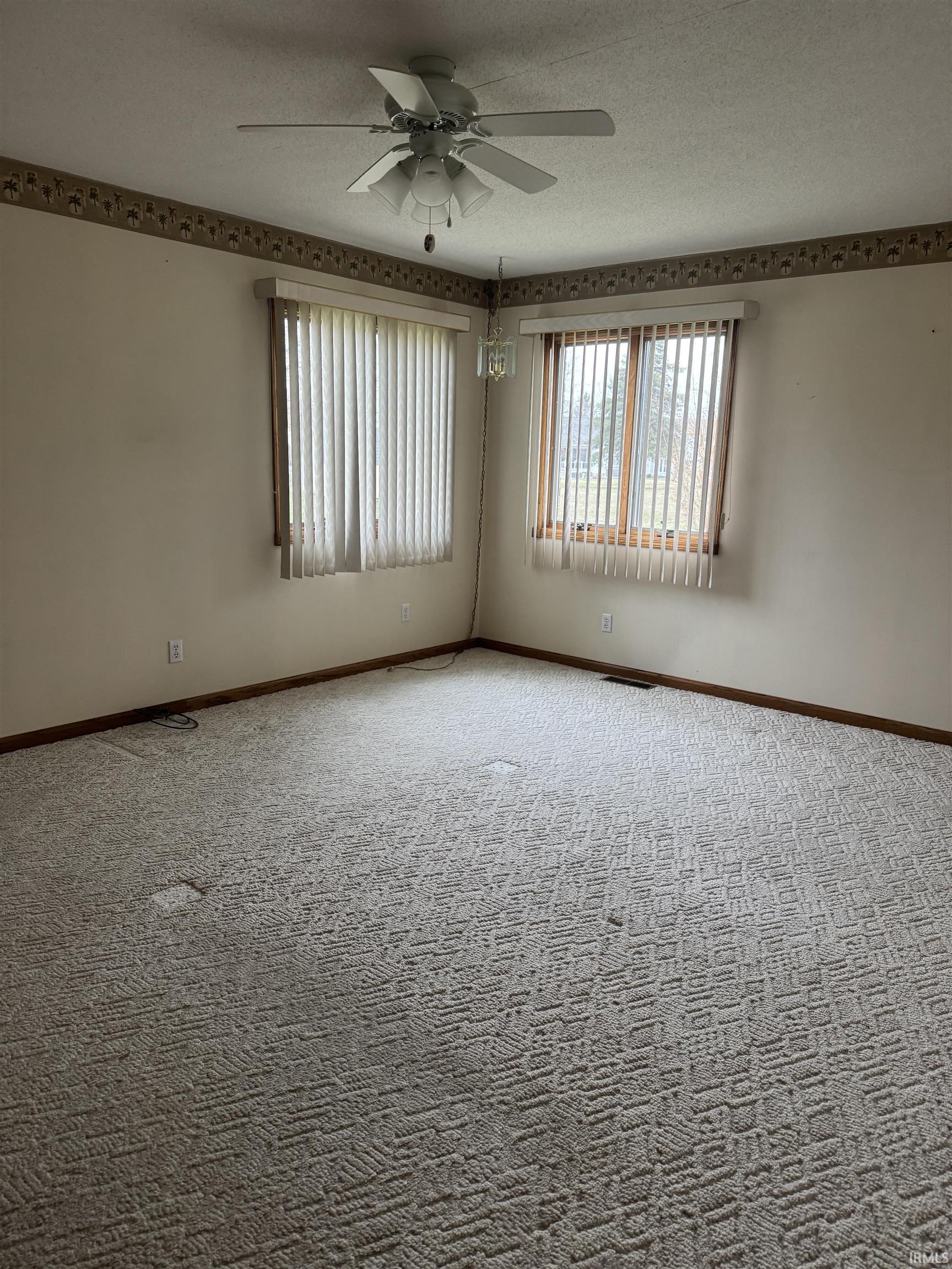 Carpeted spare room featuring a ceiling fan and a textured ceiling