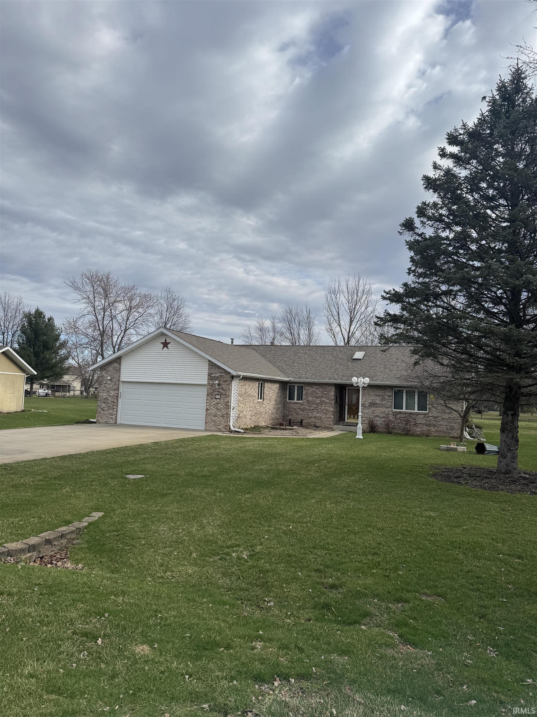 Ranch-style home featuring a garage, a front lawn, concrete driveway, and brick siding