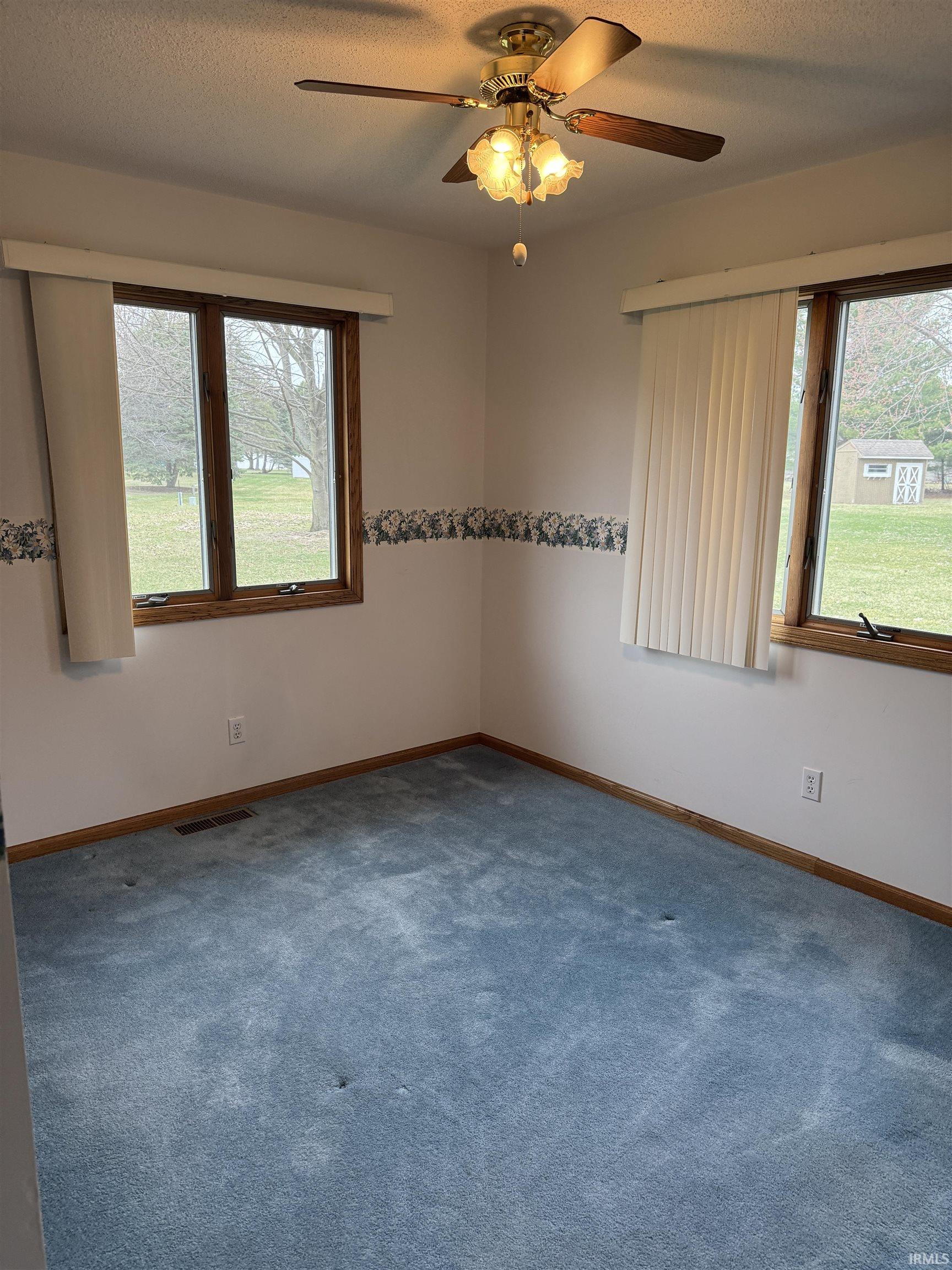 Carpeted spare room featuring a textured ceiling and ceiling fan