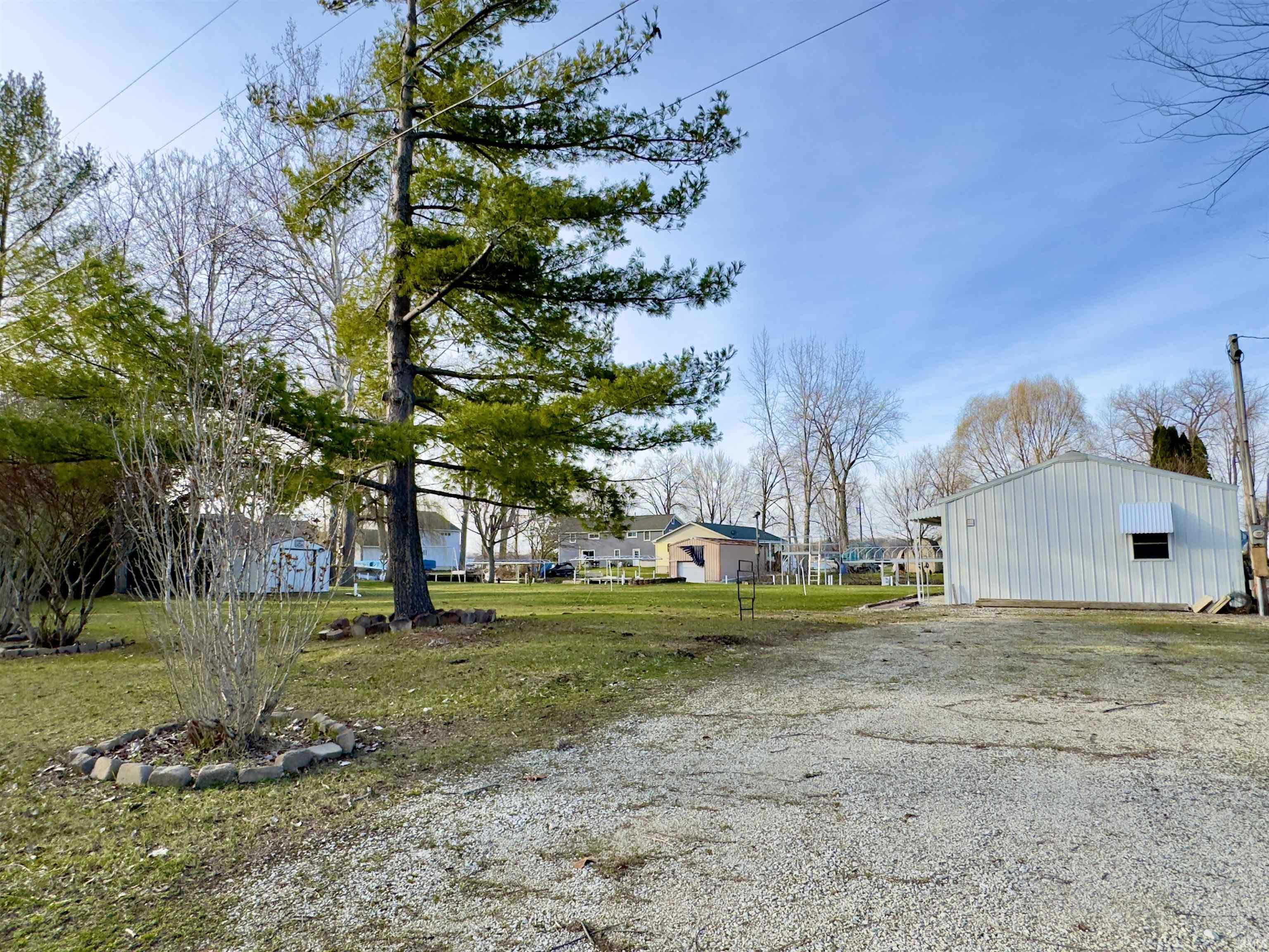View of grassy yard featuring an outbuilding and driveway
