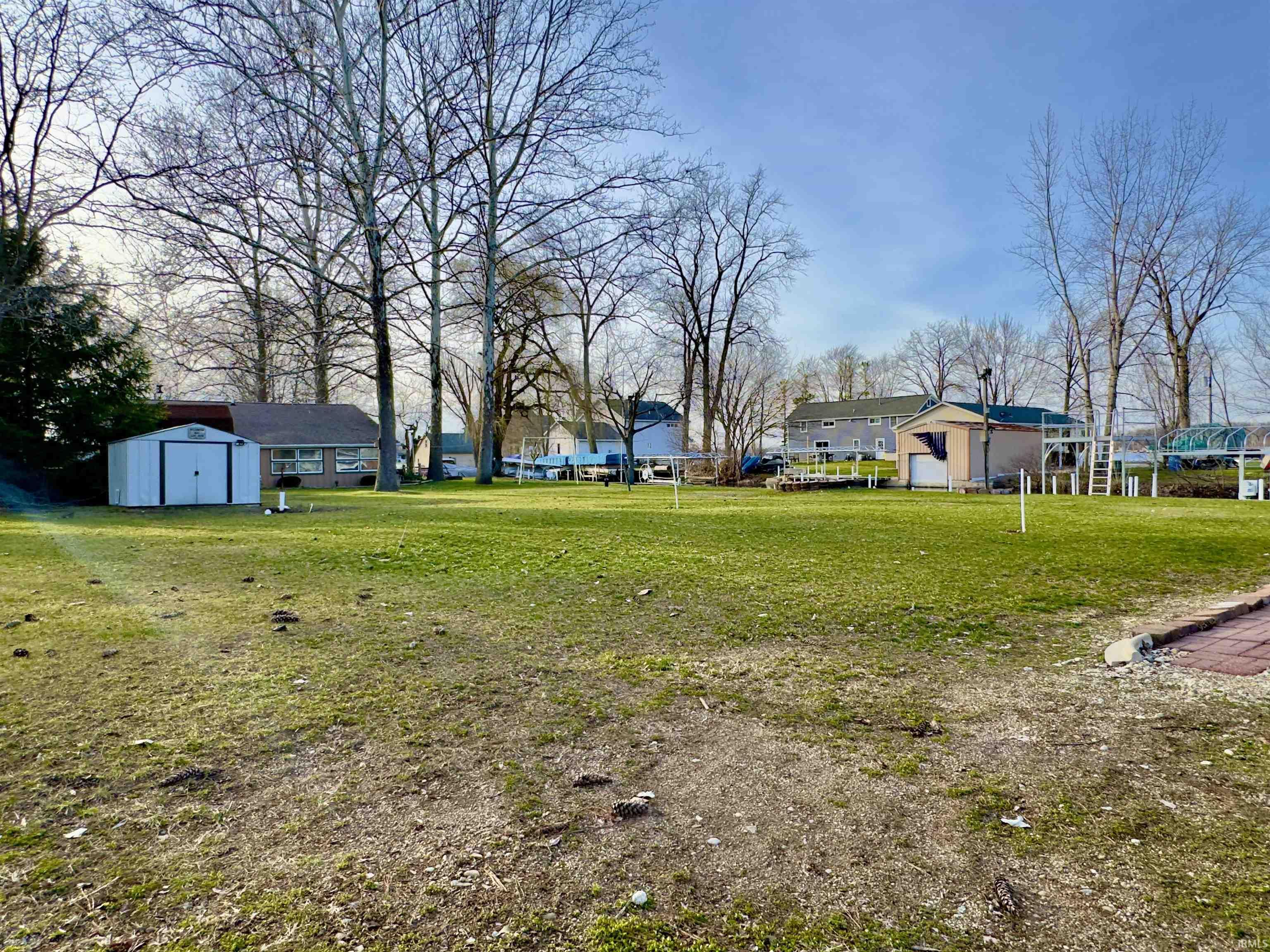 View of grassy yard featuring a storage shed and a residential view