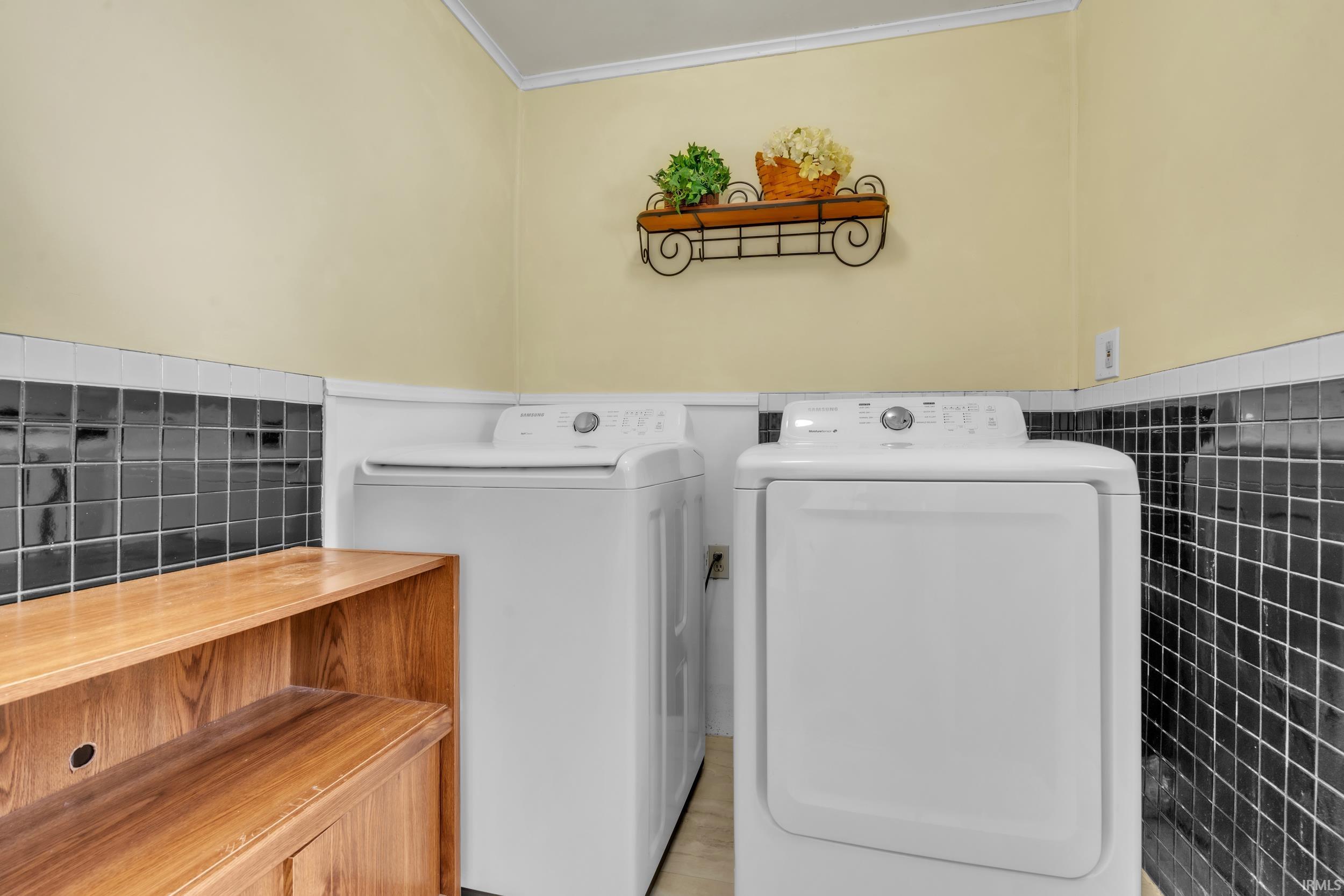 Laundry area featuring washer and dryer, a wainscoted wall, and tile walls