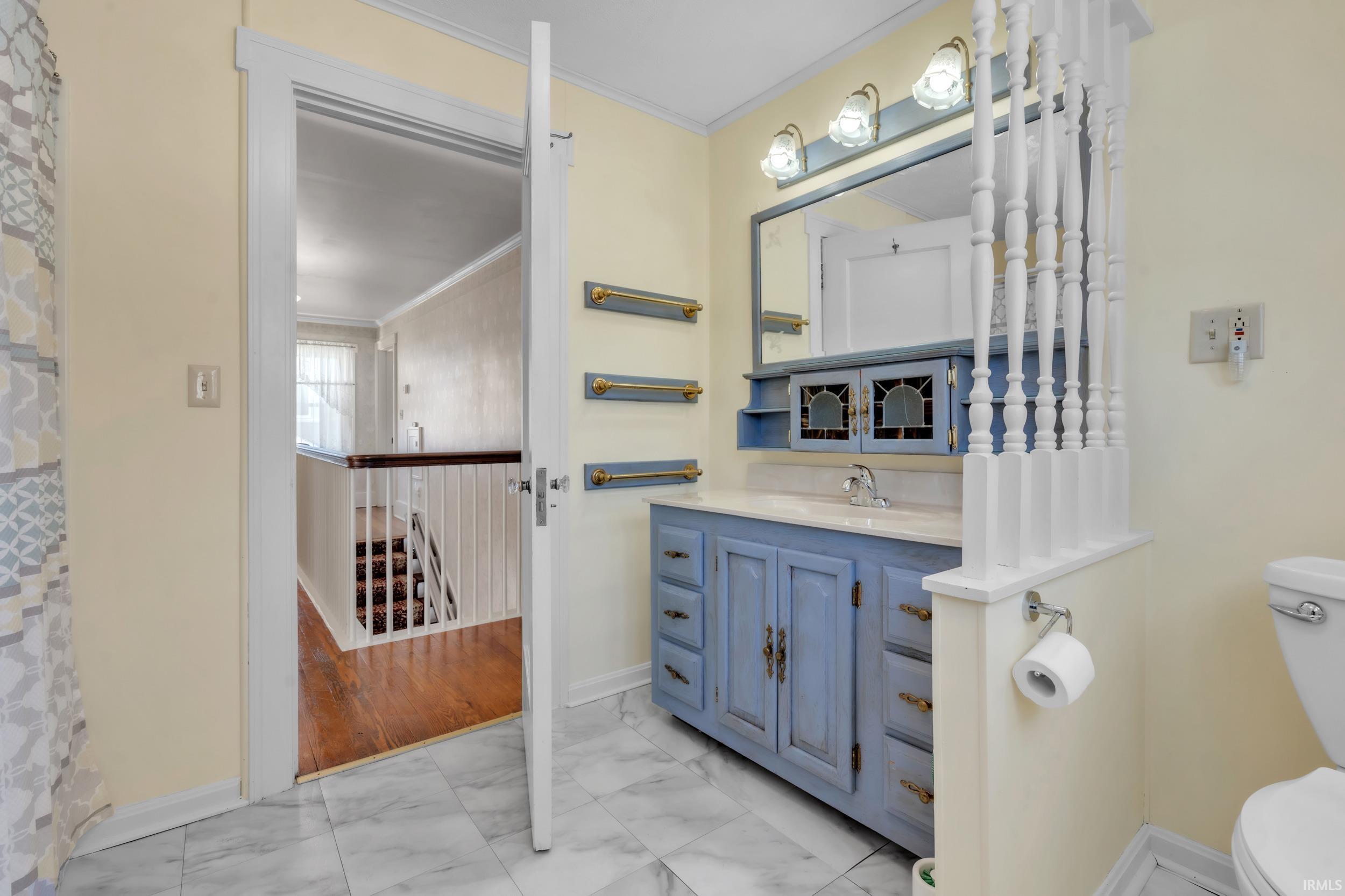Full bathroom with ornamental molding, vanity, and light marble finish flooring