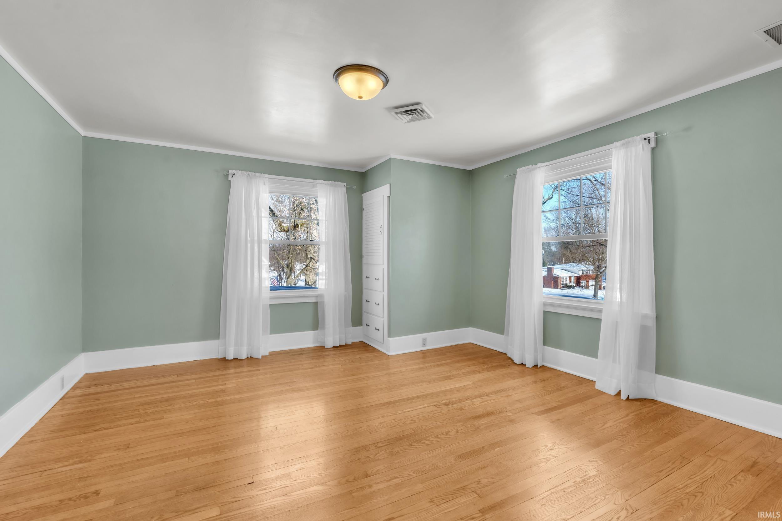 Unfurnished room with light wood finished floors and ornamental molding