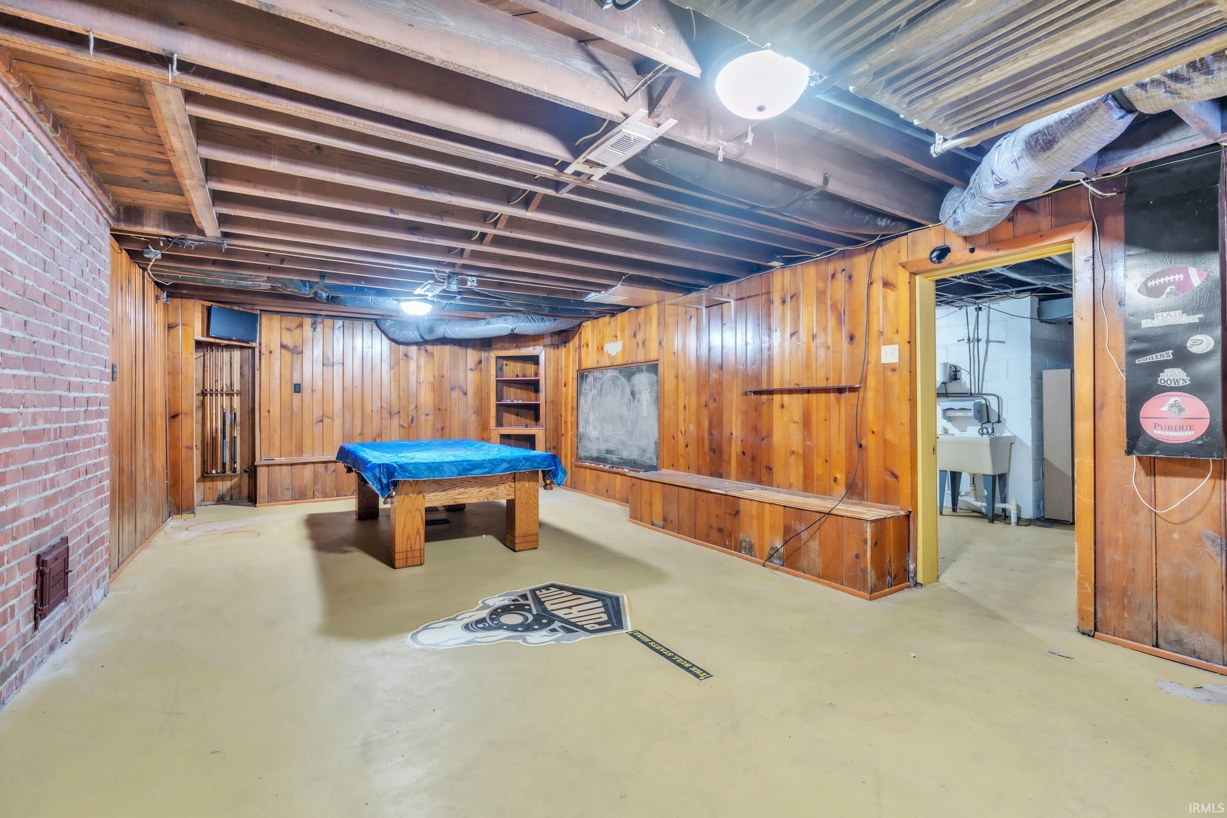 Rec room featuring wooden walls, billiards, and finished concrete floors