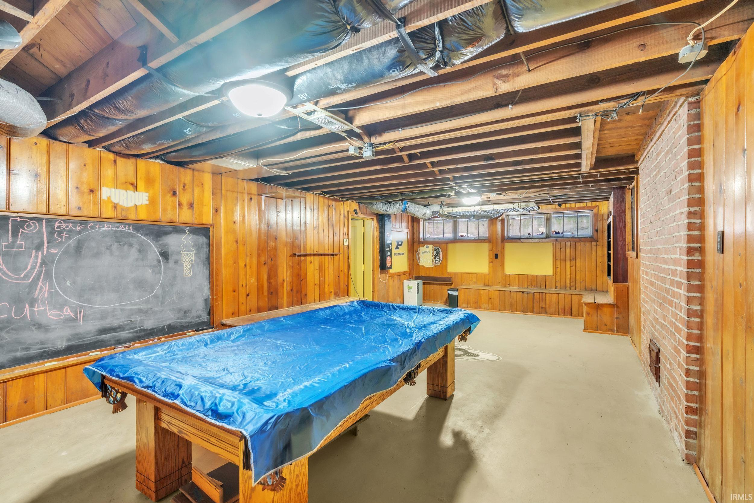 Recreation room featuring wood walls, billiards table, and concrete flooring