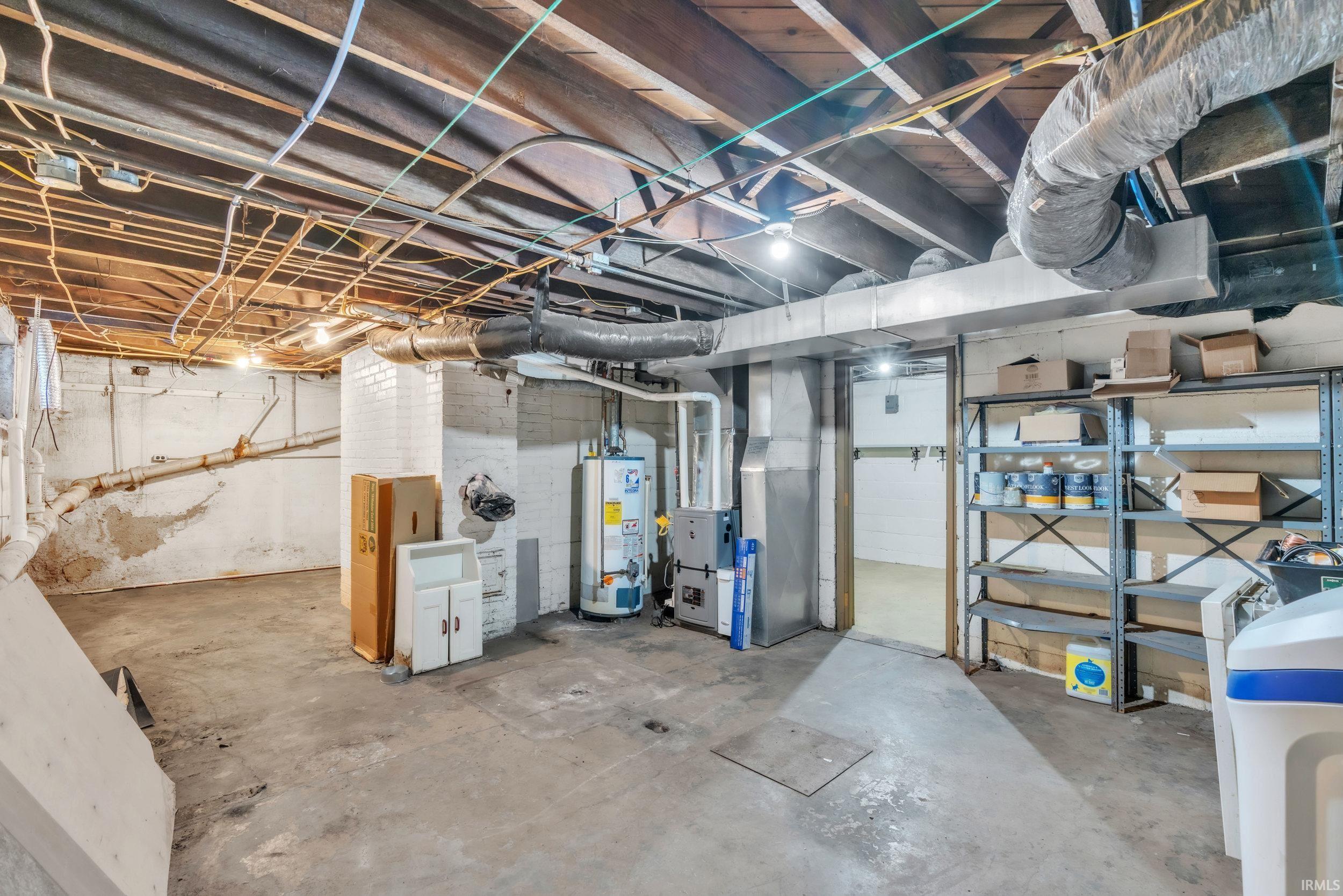 Unfinished basement with heating unit, gas water heater, and a water softener