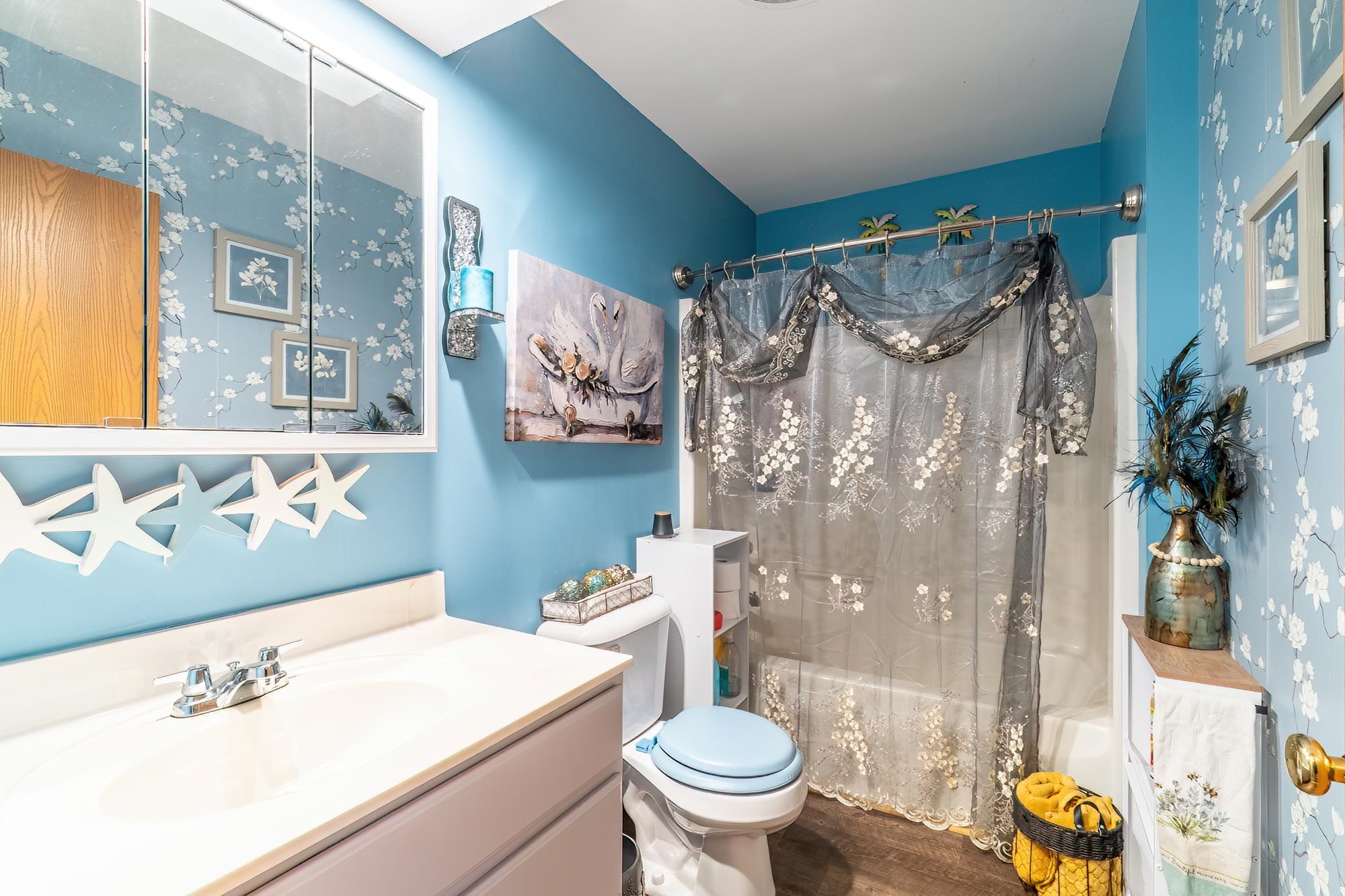Bathroom featuring shower / bath combo with shower curtain, vanity, and wood finished floors