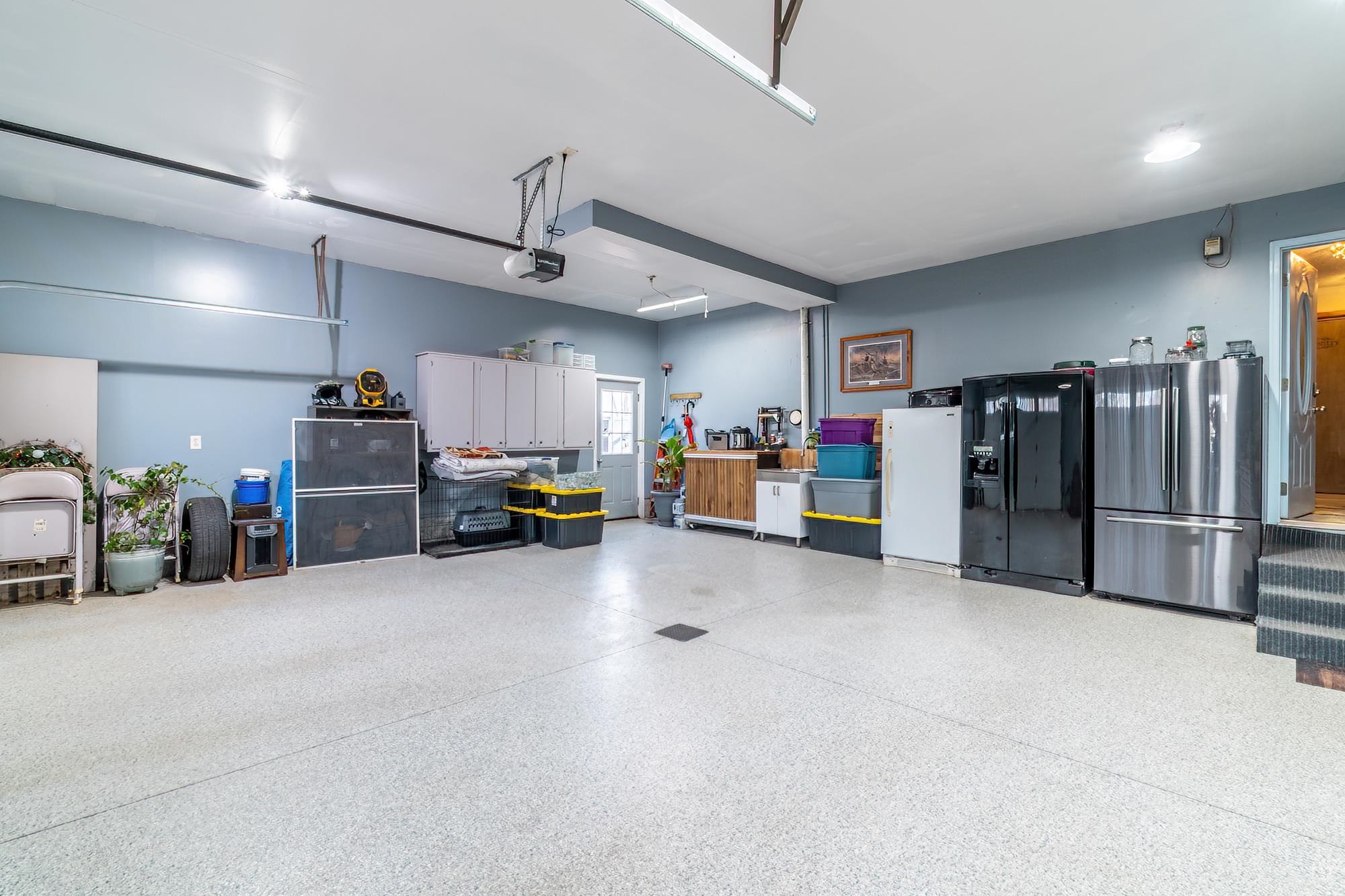 Garage featuring freestanding refrigerator, black fridge with ice dispenser, and fridge