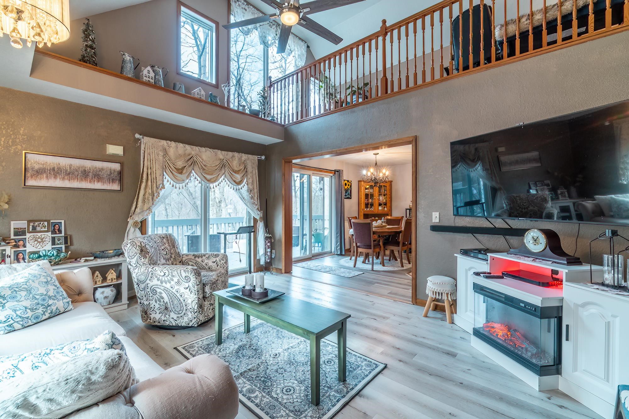 Living room featuring a chandelier, light wood finished floors, a high ceiling, and a ceiling fan
