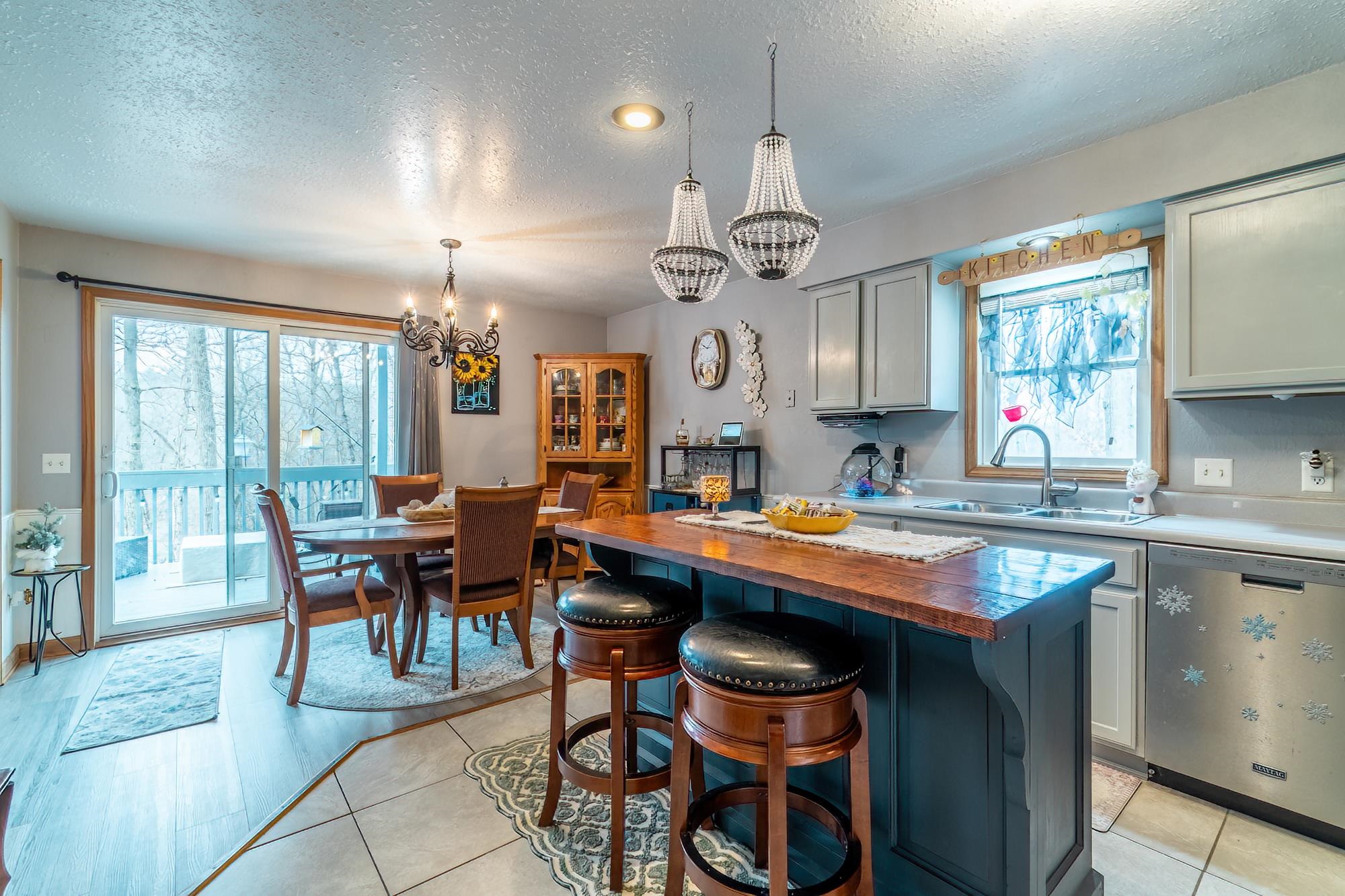 Kitchen featuring wooden counters, dishwasher, a breakfast bar area, a textured ceiling, and hanging lights