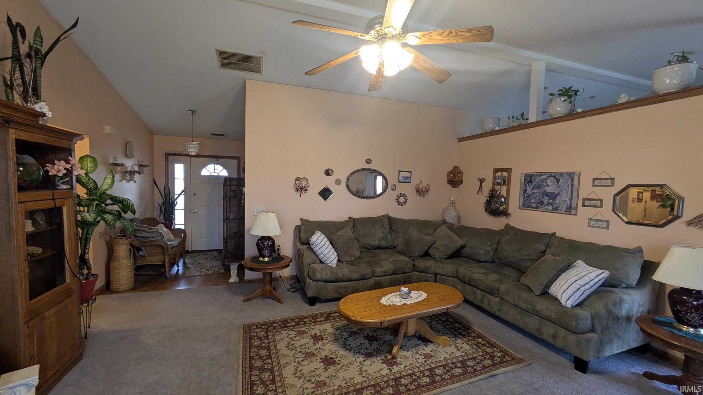 Carpeted living area with vaulted ceiling and a ceiling fan
