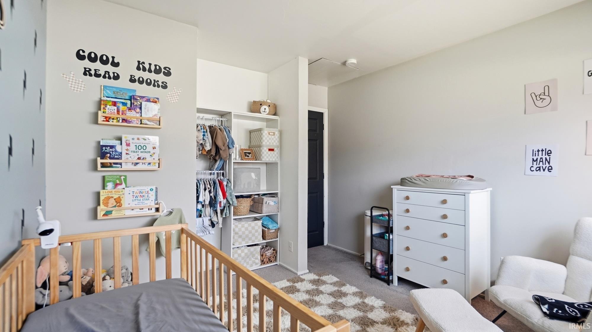 Bedroom featuring a nursery area, light carpet, and a closet