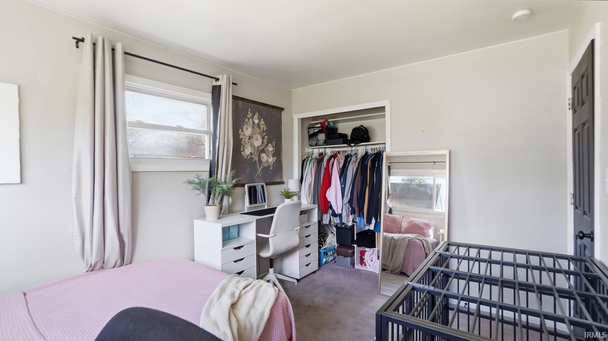 Carpeted bedroom with a closet and a desk