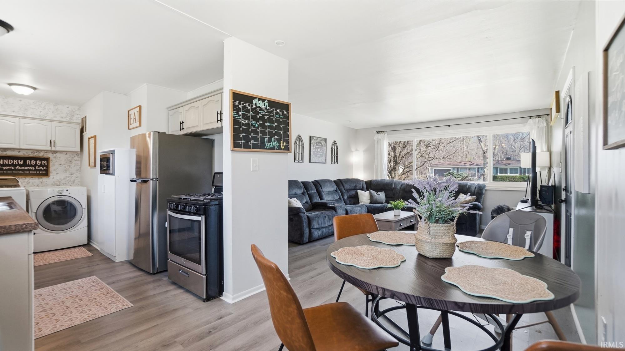 Dining room with washer / dryer, light wood-type flooring, and wallpapered walls