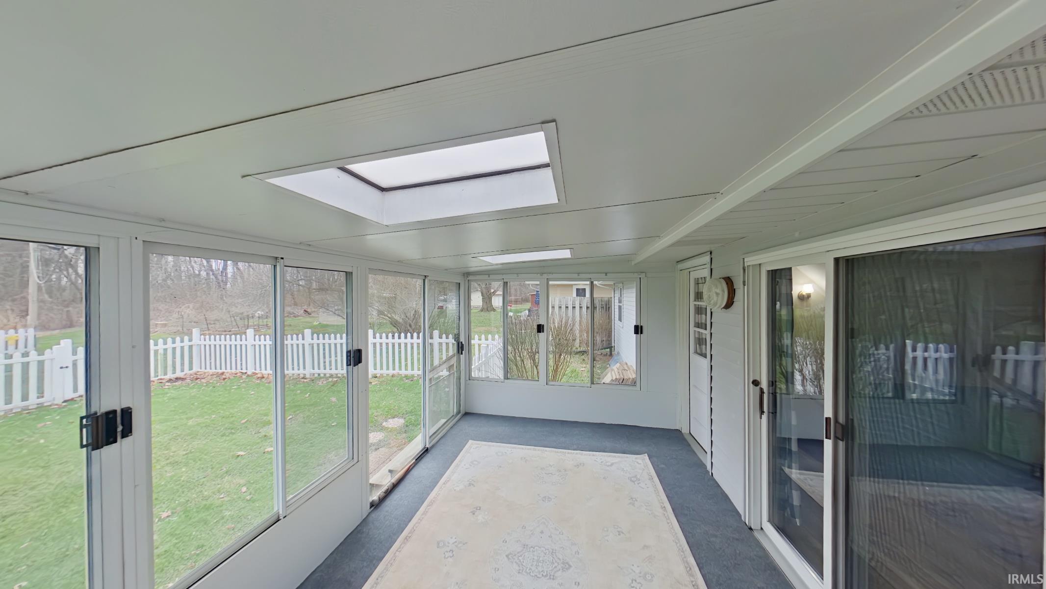 Unfurnished sunroom featuring carpet flooring and a skylight