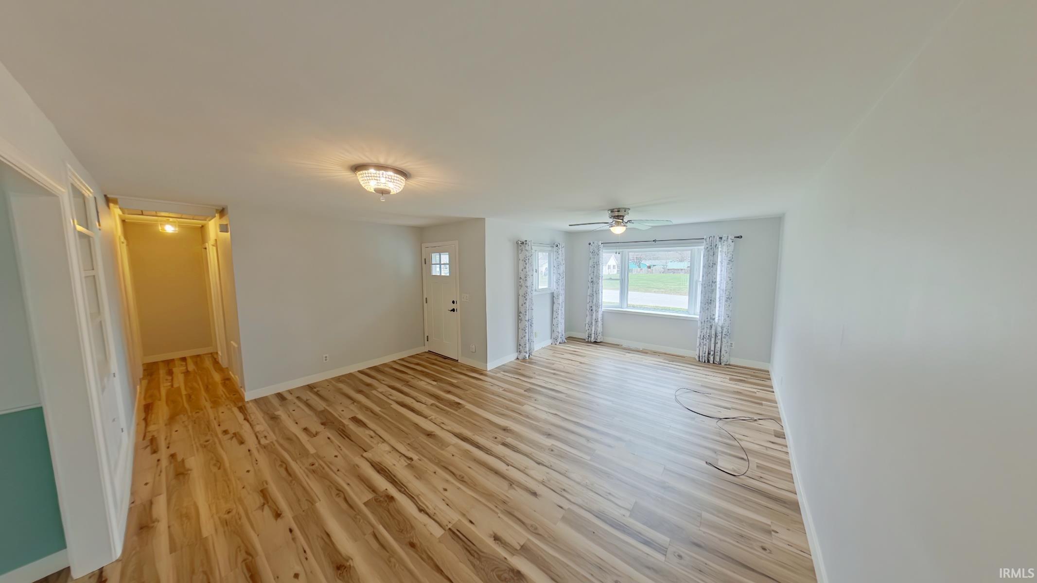 Unfurnished living room featuring light wood-style flooring and ceiling fan