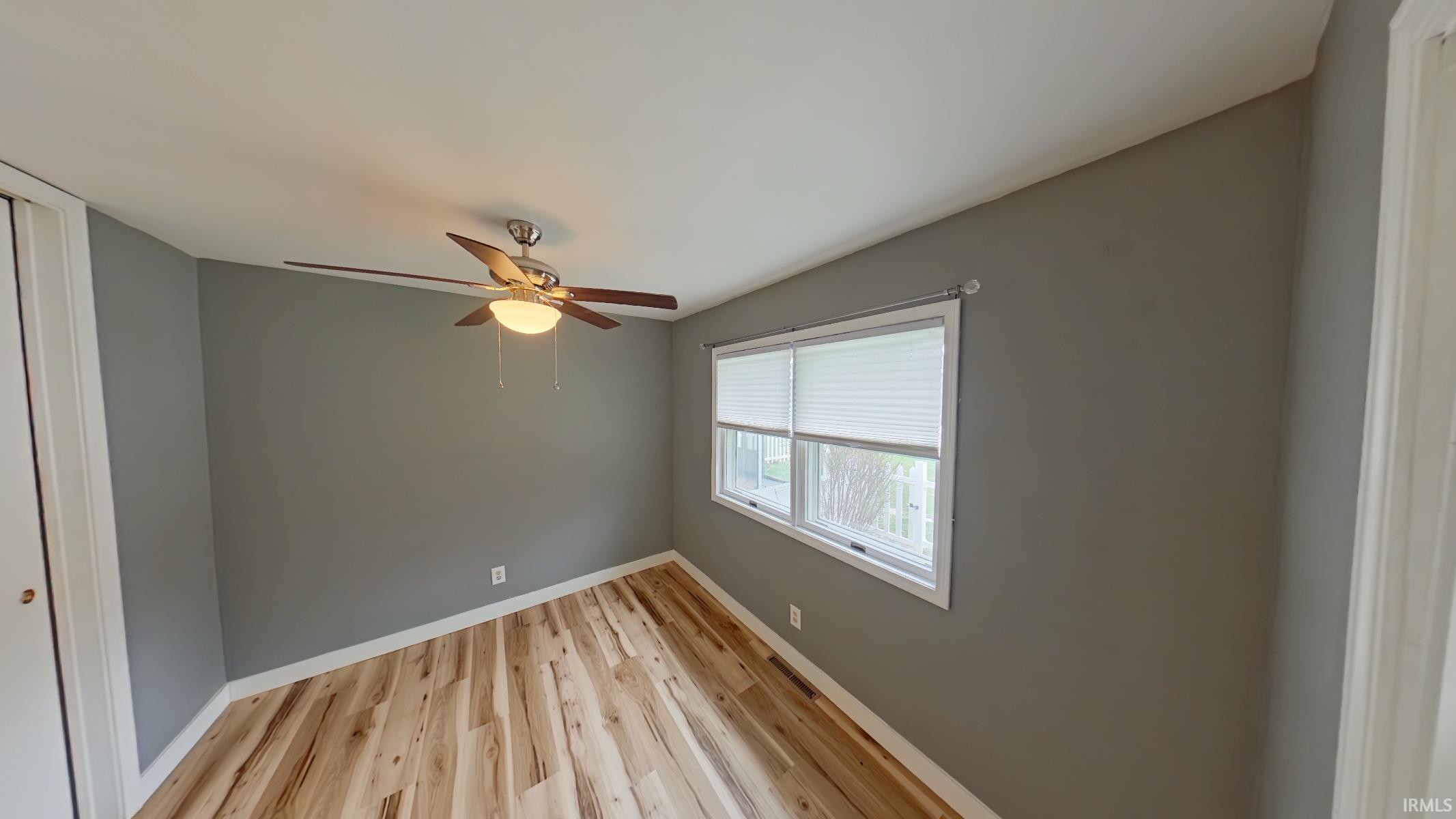 Empty room with light wood-type flooring and a ceiling fan