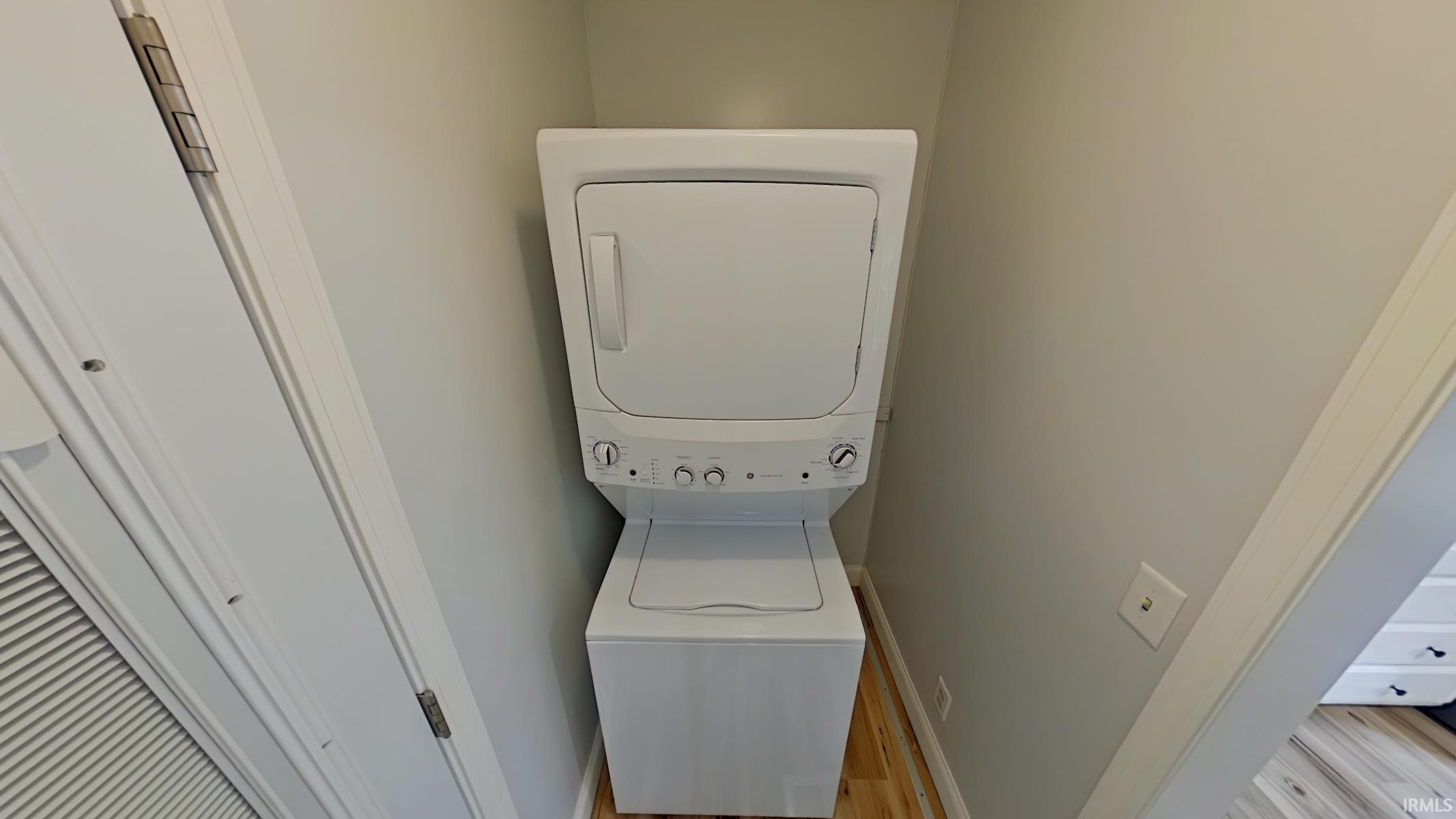 Laundry area featuring stacked washer / drying machine and light wood-type flooring
