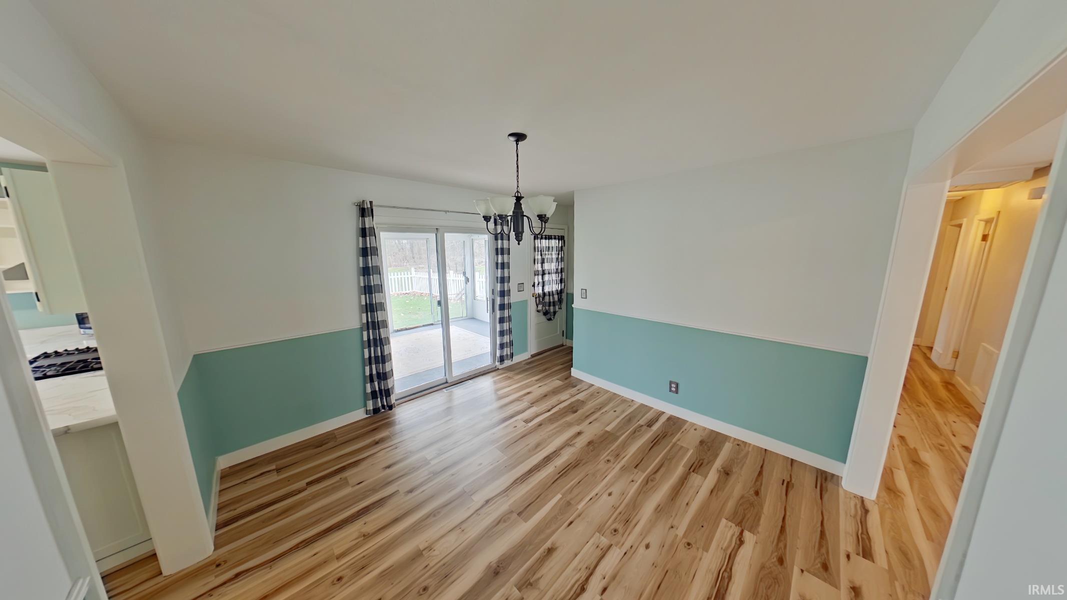 Unfurnished dining area with suspended lighting and light wood finished floors
