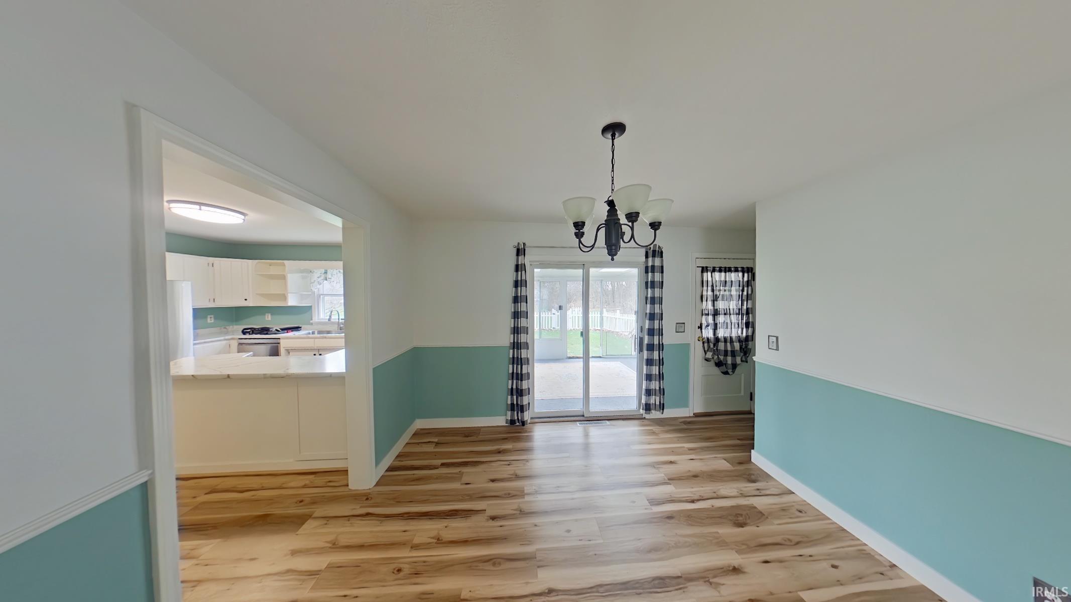 Unfurnished dining area with suspended lighting and light wood finished floors