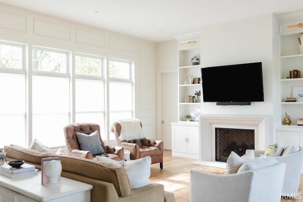 Living area featuring built in features, wood finished floors, and a fireplace