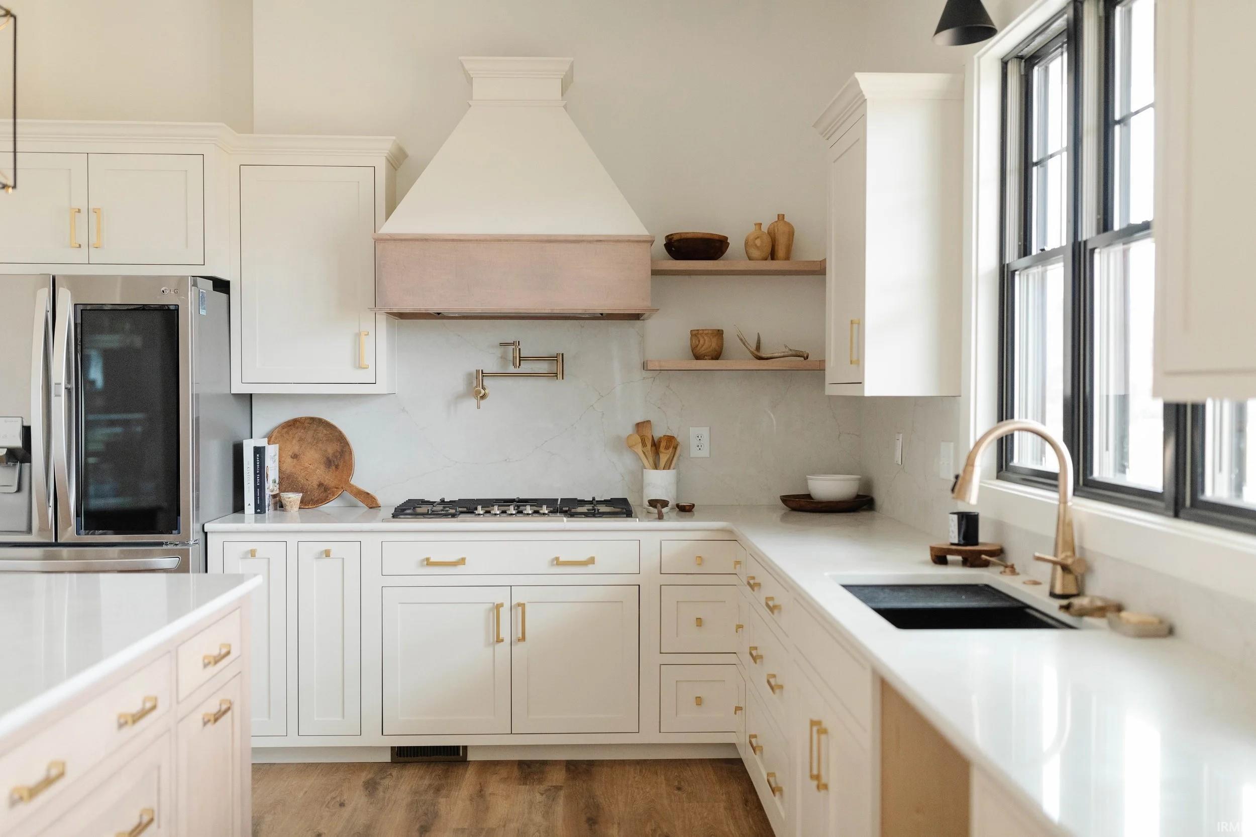 Kitchen featuring stainless steel appliances, white cabinets, light wood-type flooring, open shelves, and light stone counters