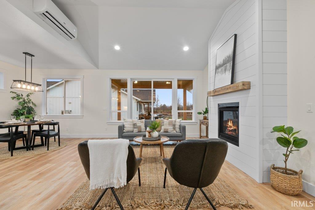 Living room with vaulted ceiling, light wood-style floors, a fireplace, and recessed lighting